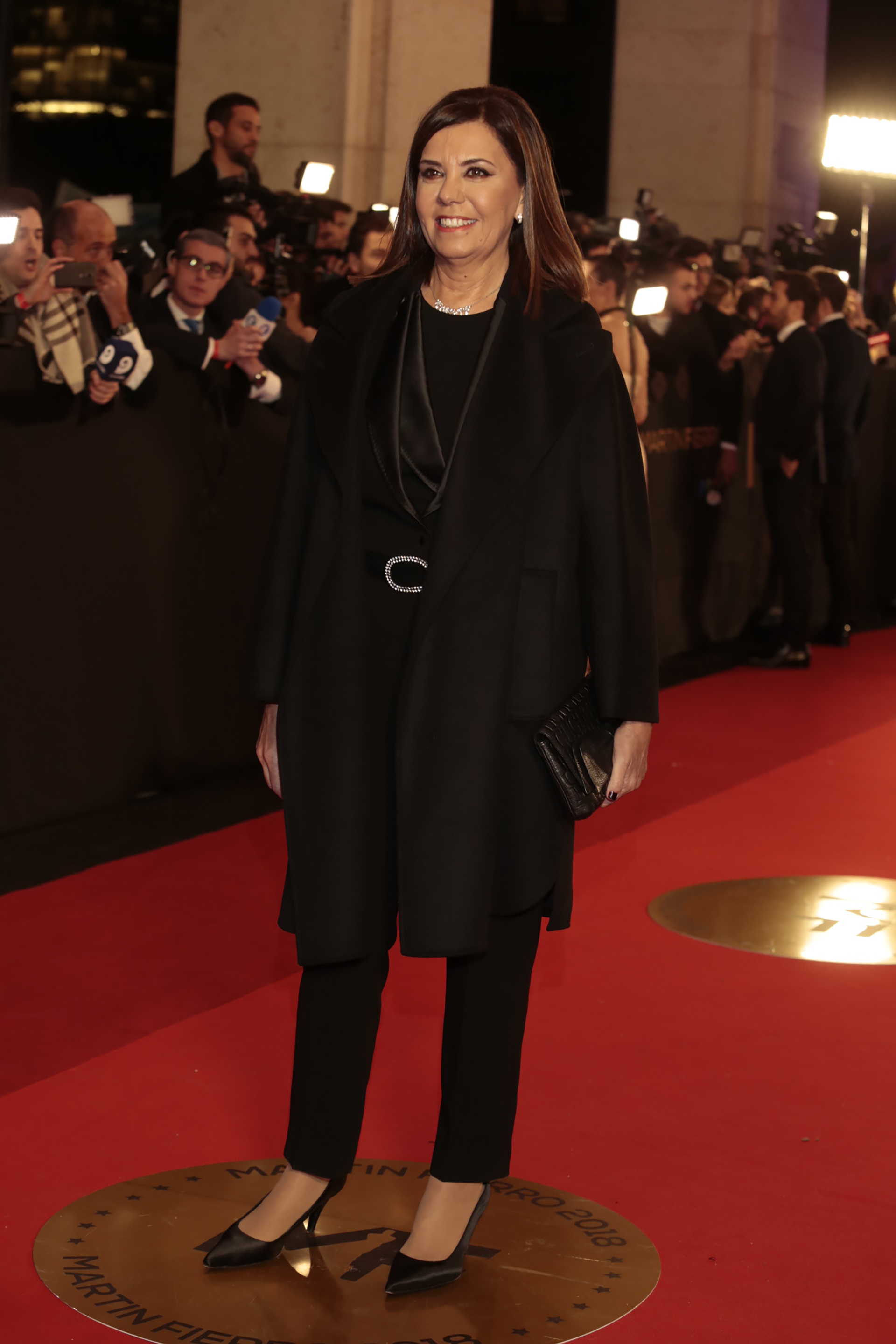 Liliana Parodi eligió un smoking femenino en total black. Lo combinó con tapado, stilettos de raso en punta y clutch de cuero.