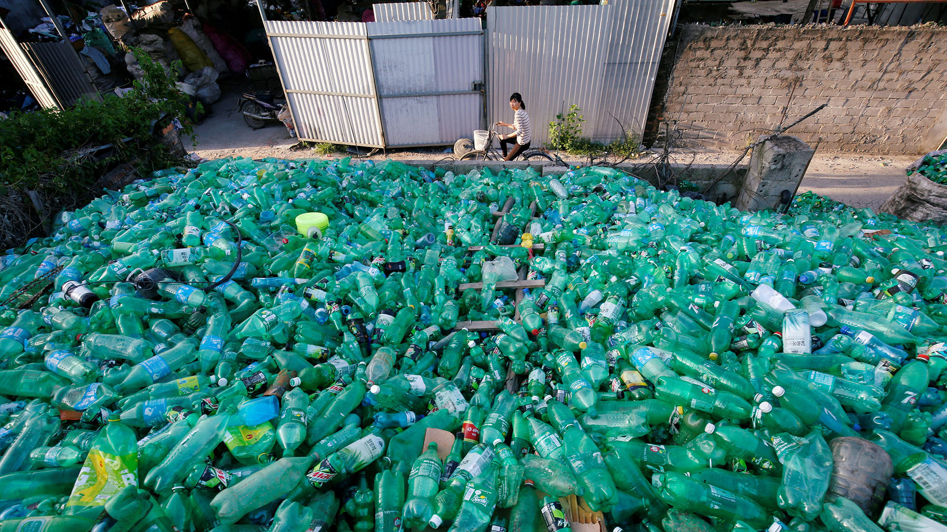 Una mujer vietnamita pasa con su bicicleta junto a una montaña de botellas plásticas en la ciudad de Xa Cau village, en las afuera de Hanoi, Vietnam (REUTERS/Kham)