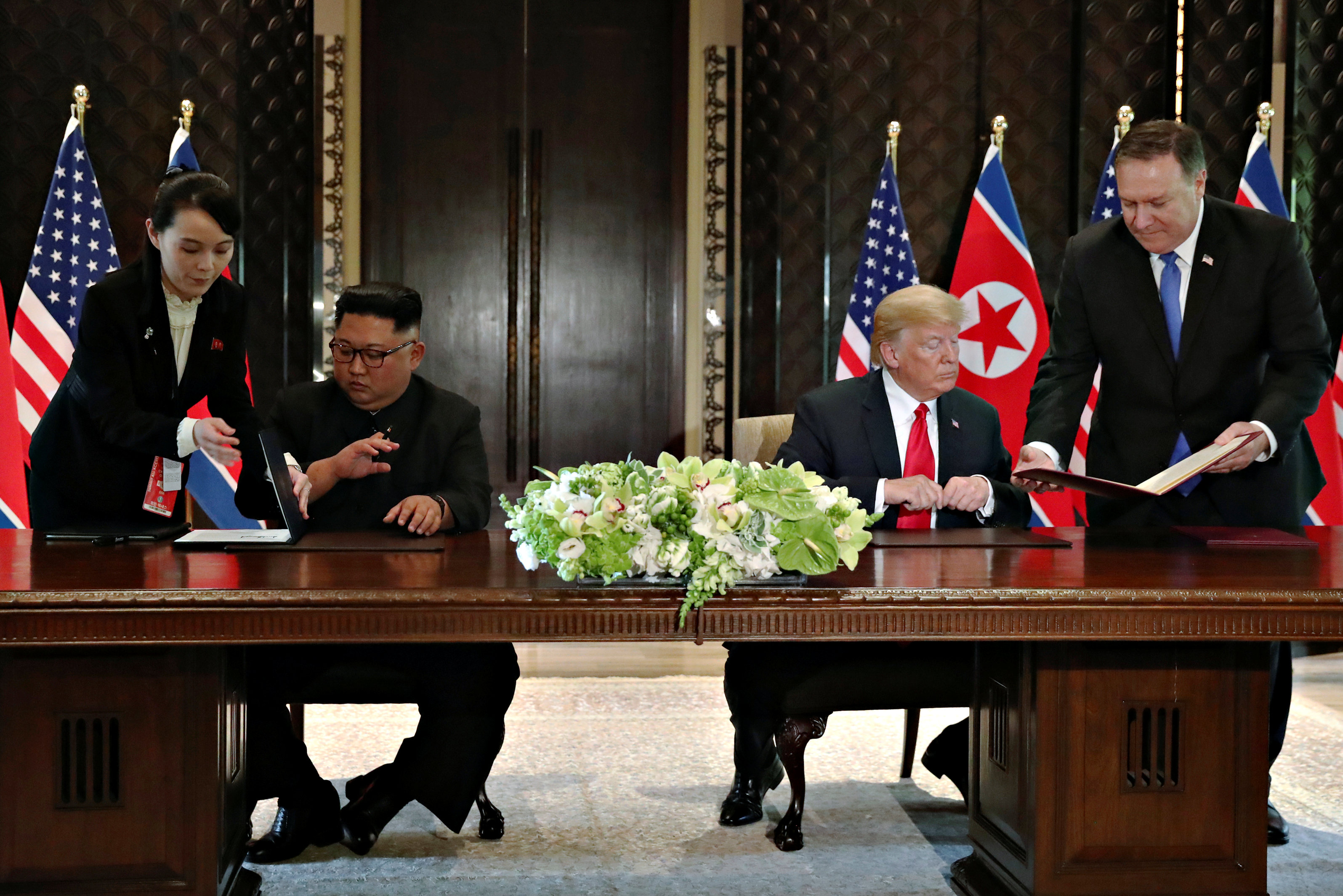 Kim Jong-un, acompañado de su hermana Kim Yo-jong, firma al declaración de Singapur junto a Donald Trump, acompañado por el Secretario de Estado Mike Pompeo (Reuters)