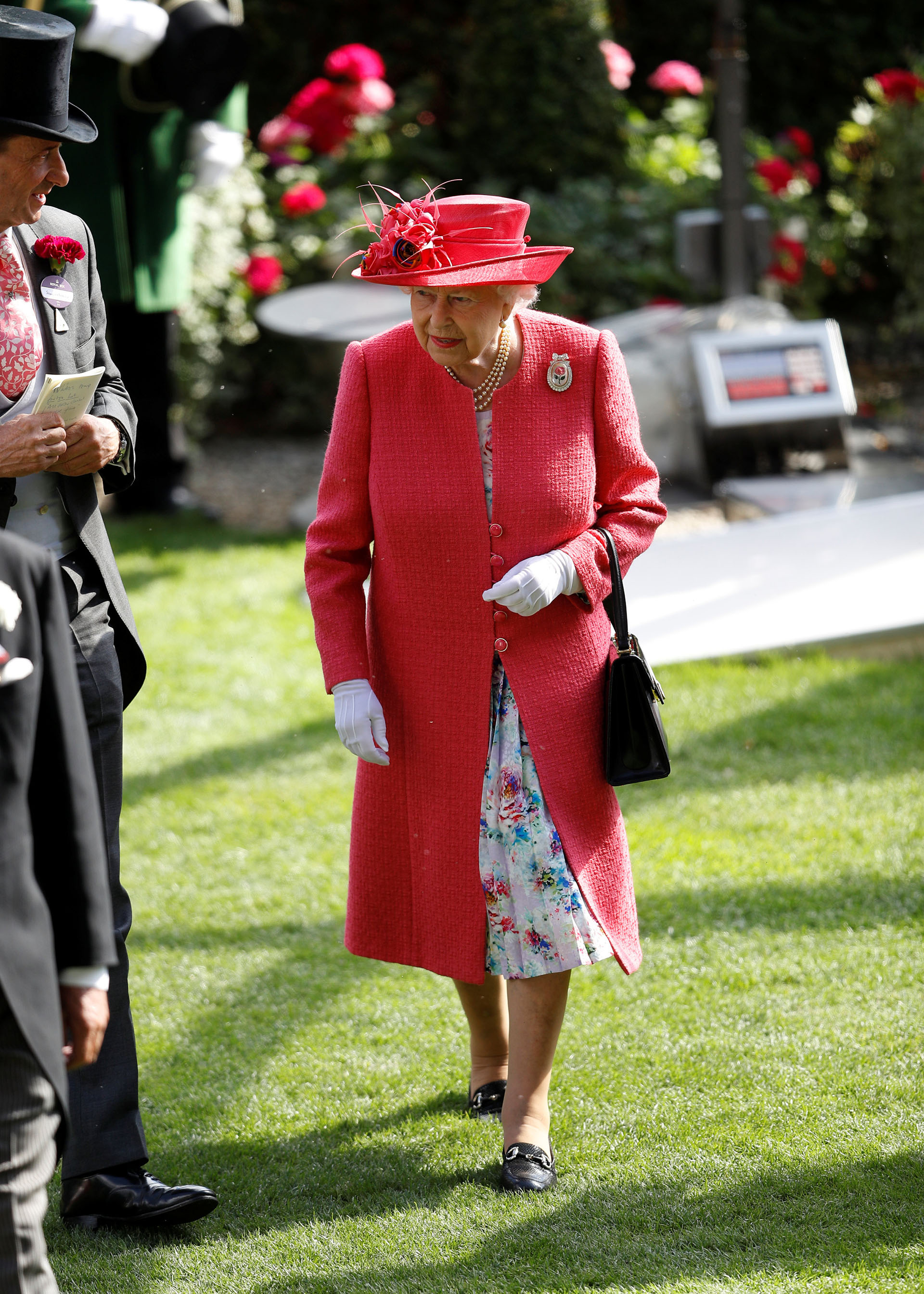 La reina lució un tapado rosa que hacía juego con su sombrero y dejaba ver un vestido con estampa floral