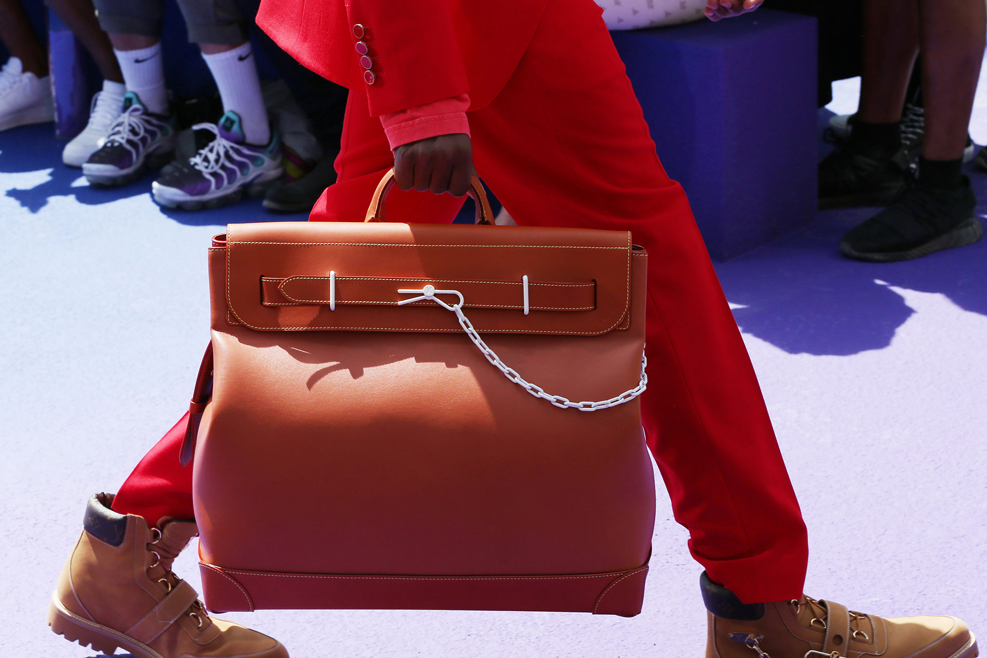Un modelo similar al Birkin de Hermes en cuero liso, con detalles de cadena y envivados en amarillo