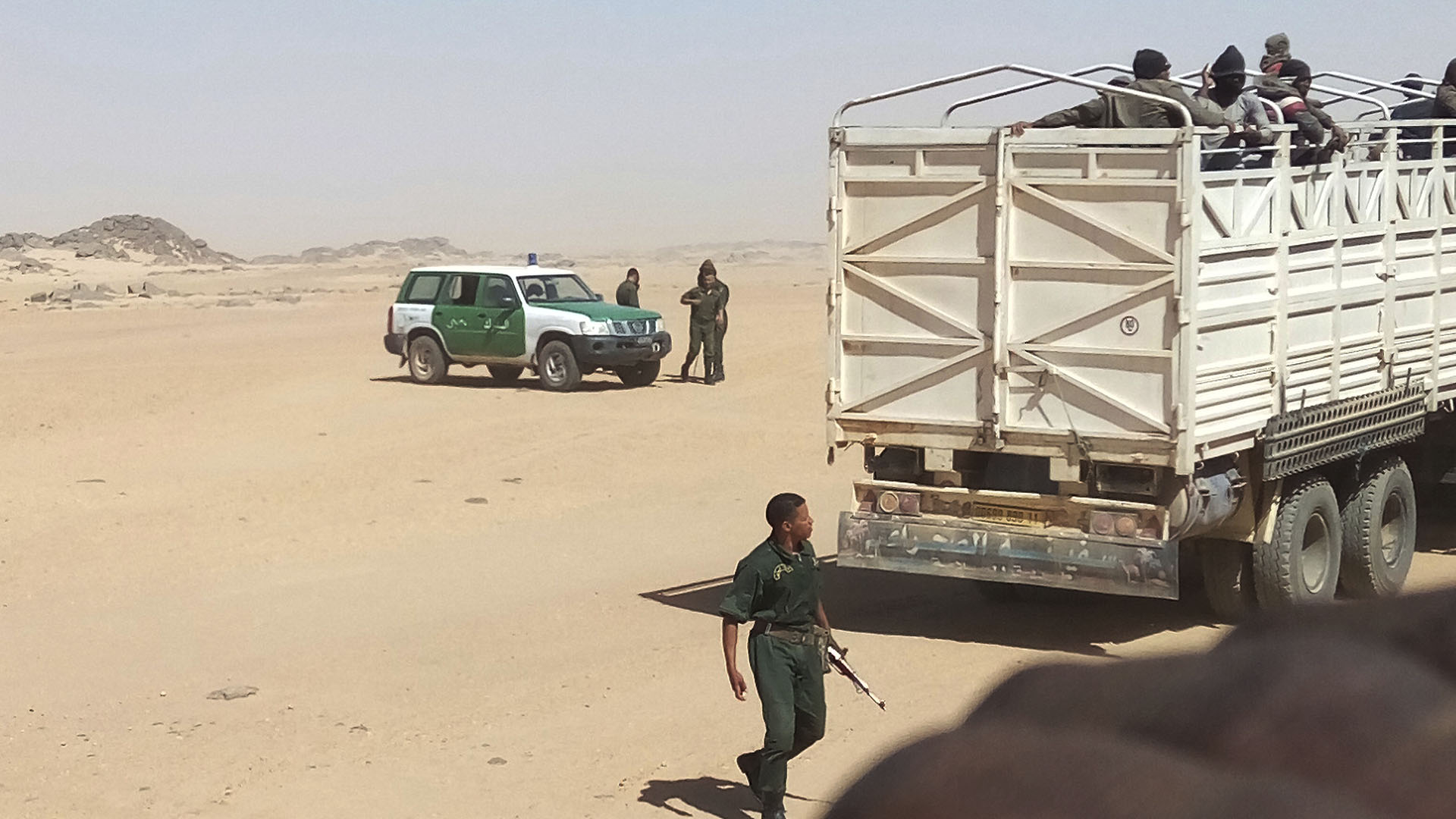 Soldados argelinos armados con rifles de fabricación rusa colocan a los migrantes en camiones y los abandonan en la frontera con Níger, en medio del desierto (AP)