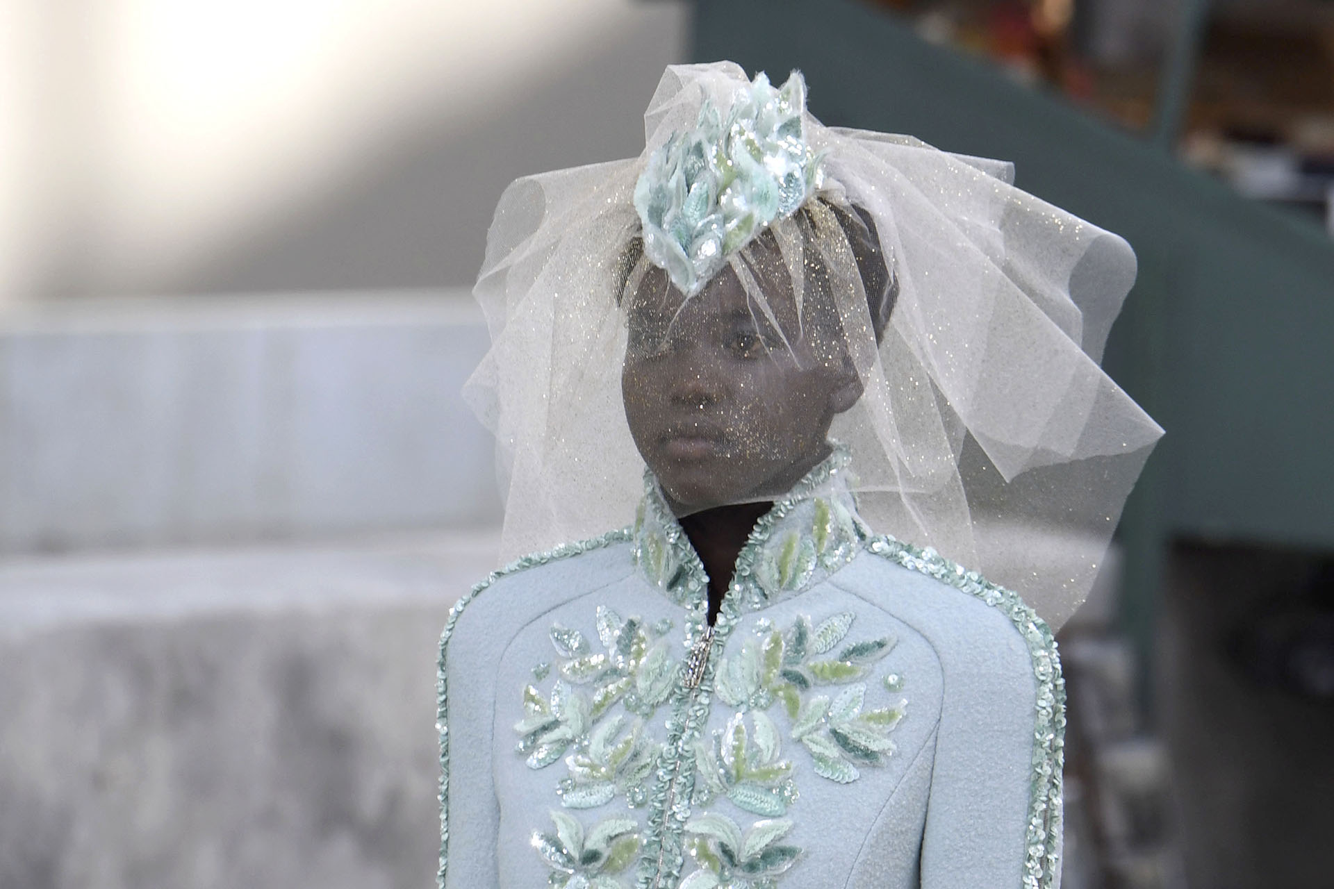 Adut Akech, la modelo sudafricana-australiana, estuvo presente en el desfile de Chanel y lució un diseño de chaqueta de paño con detalles únicos de bordados en tonos celeste hielo y verdes. Los tocados de la colección presentada por Karl Lagerfeld llamaron la atención por la originalidad y la perfecta combinación con los equipos