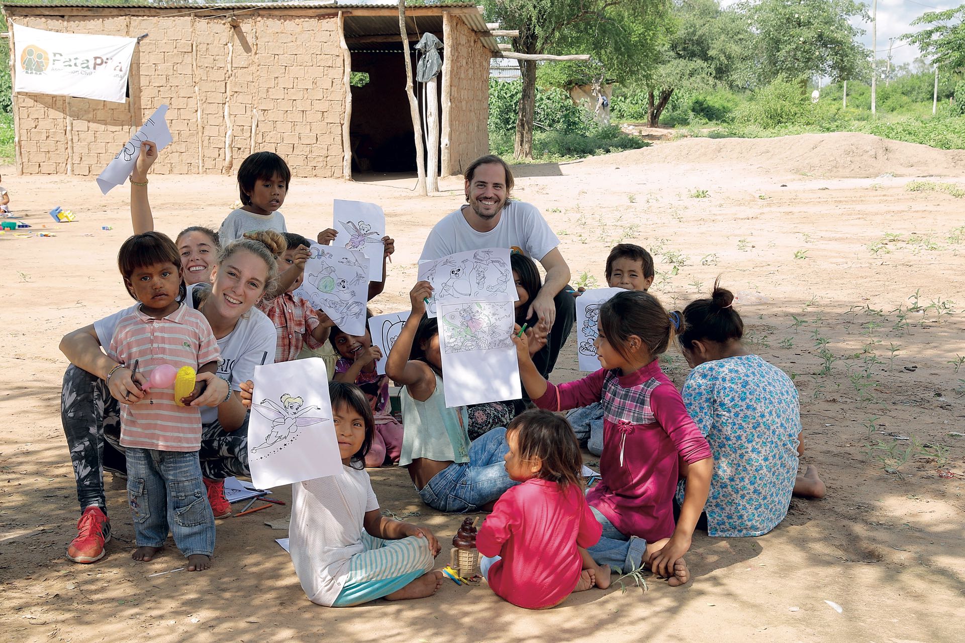 Diego Bustamante junto con otros voluntarios de la ONG y los niños que muestran sus dibujos.