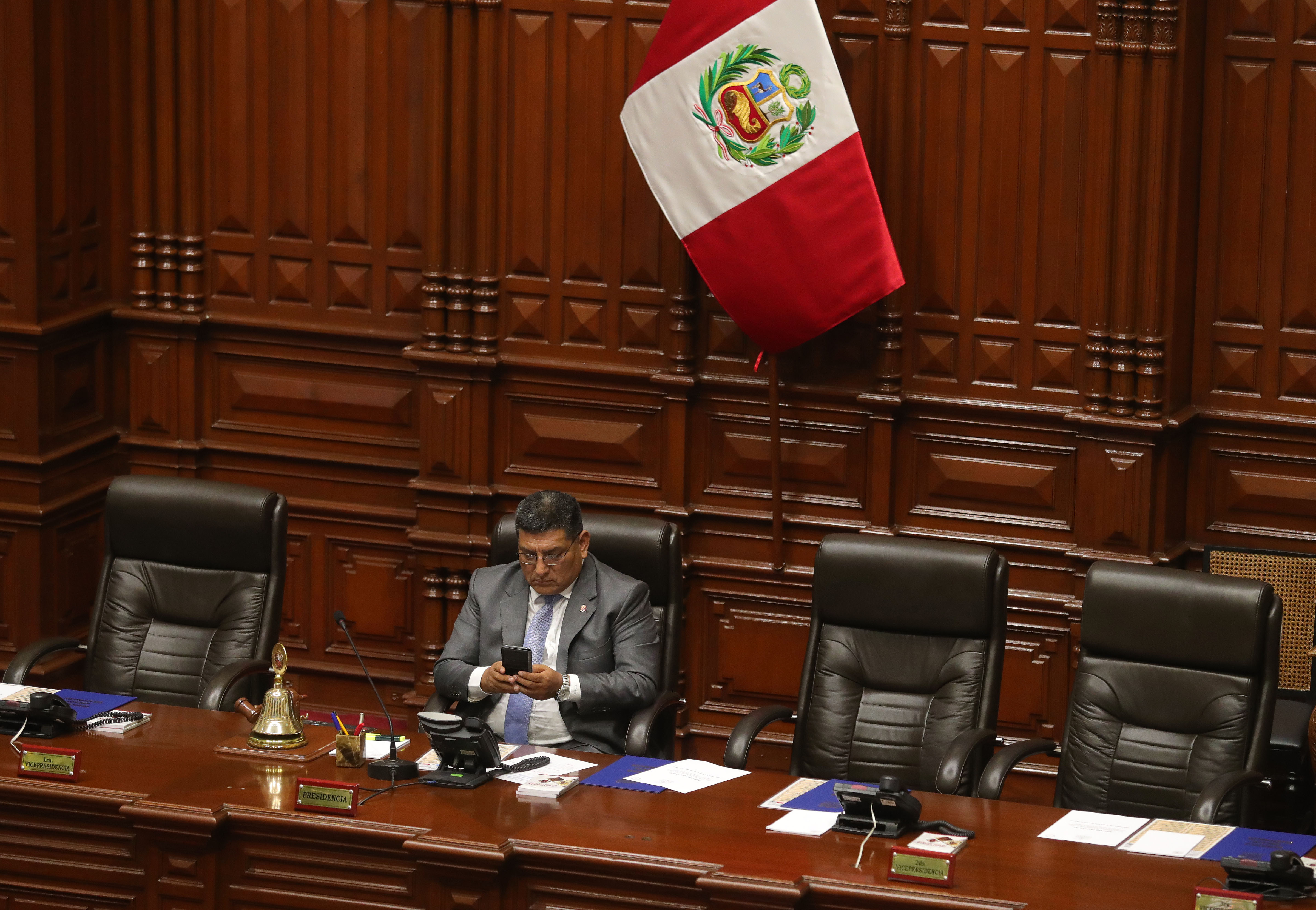 El congresista y primer vicepresidente del congreso, Mario Mantilla, utiliza su teléfono durante su participación en el pleno del Congreso en Lima. (EFE/Ernesto Arias)