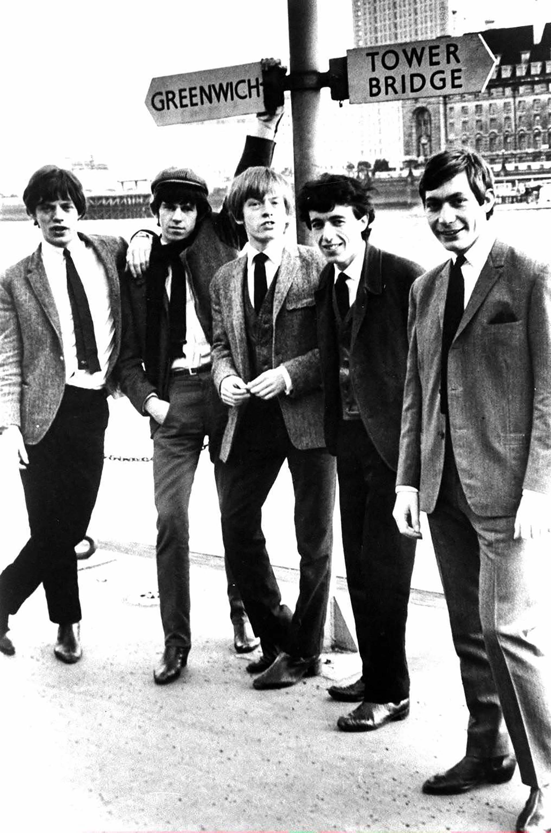 The Rolling Stones posa bajo un letrero para las calles Greenwich y Tower Bridge en Londres, Inglaterra, alrededor de 1963