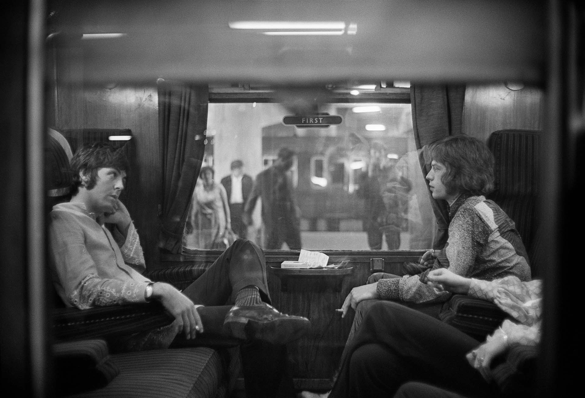 25 de agosto de 1967: Paul McCartney de los Beatles y Mick Jagger de los Rolling Stones se sientan uno frente al otro en un tren en la estación de Euston, esperando la partida a Bangor