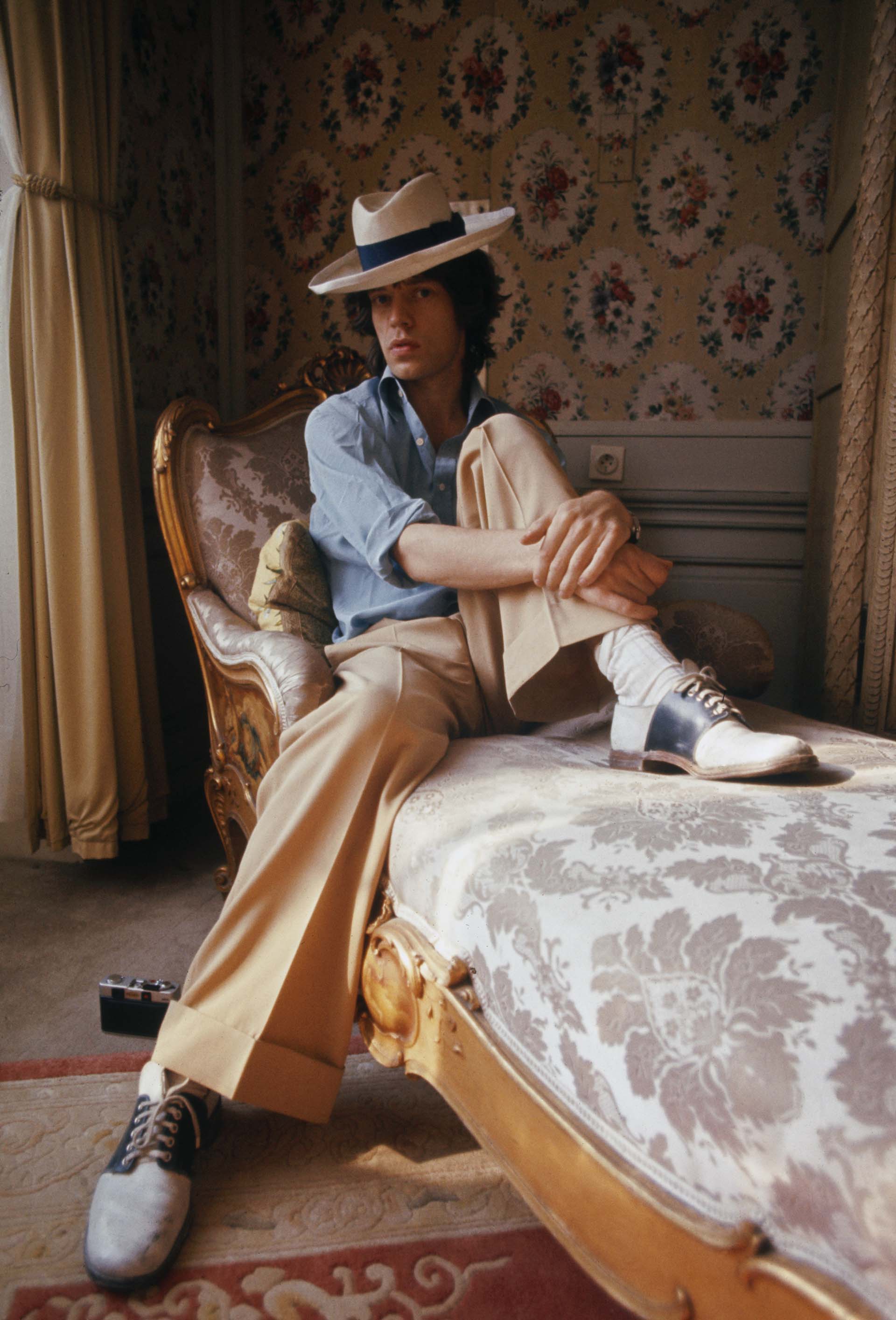 Mick Jagger, sentado en una chaise longue con un sombrero de Panamá y zapatos de dos tonos, octubre de 1973.