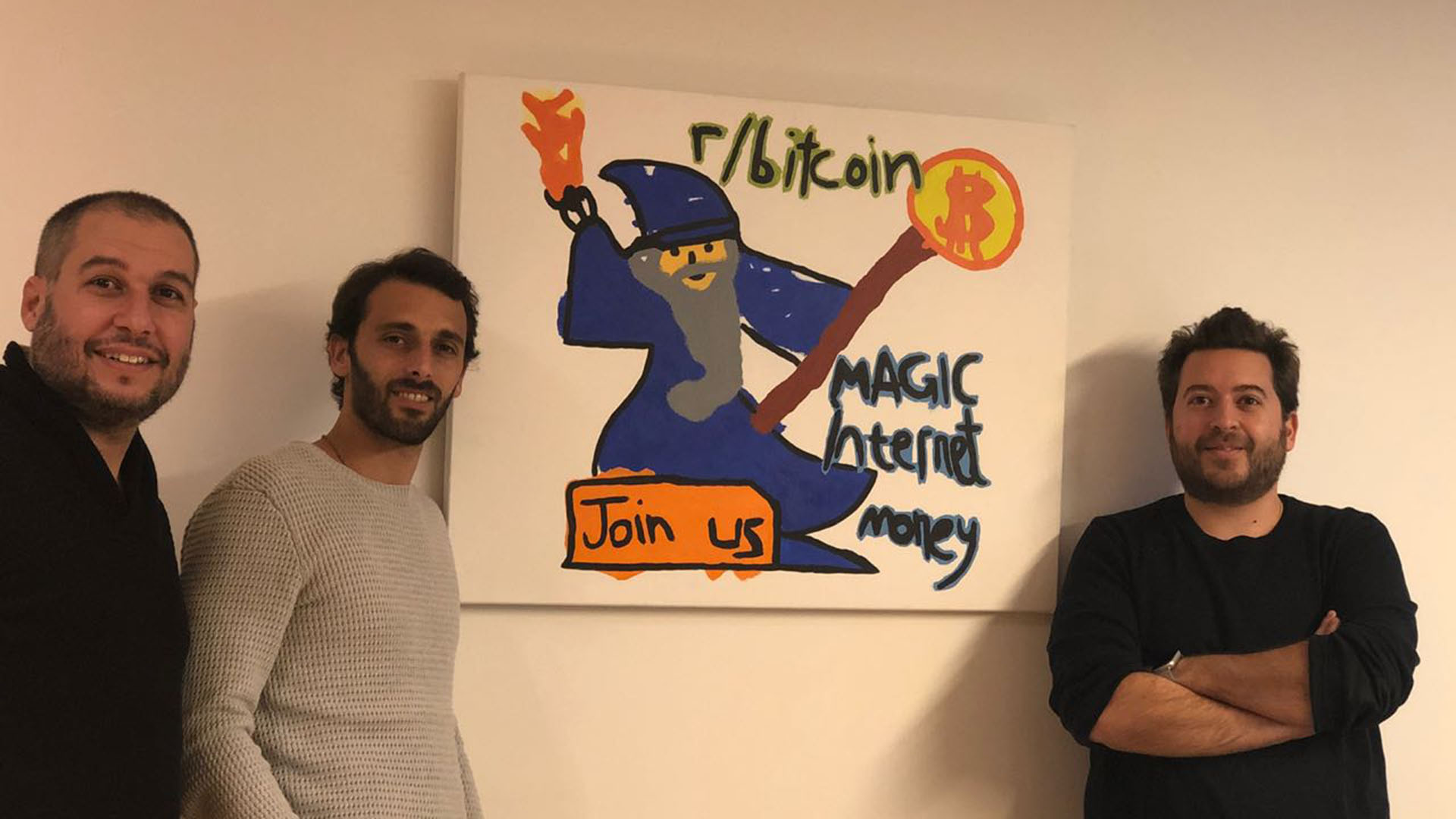 Matías Bari, Nicolás Loterspil y Mariano Craiem en las oficinas de SatoshiTango junto al cuadro con el famoso dibujo para promocionar bitcoin en la red social Reddit