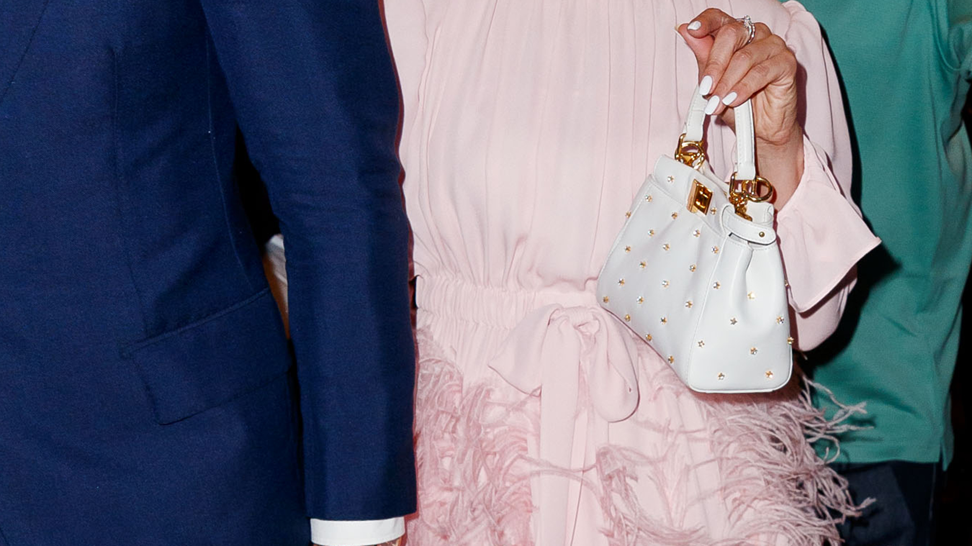 El detalle de su pequeña cartera de mano blanca, con detalles oro