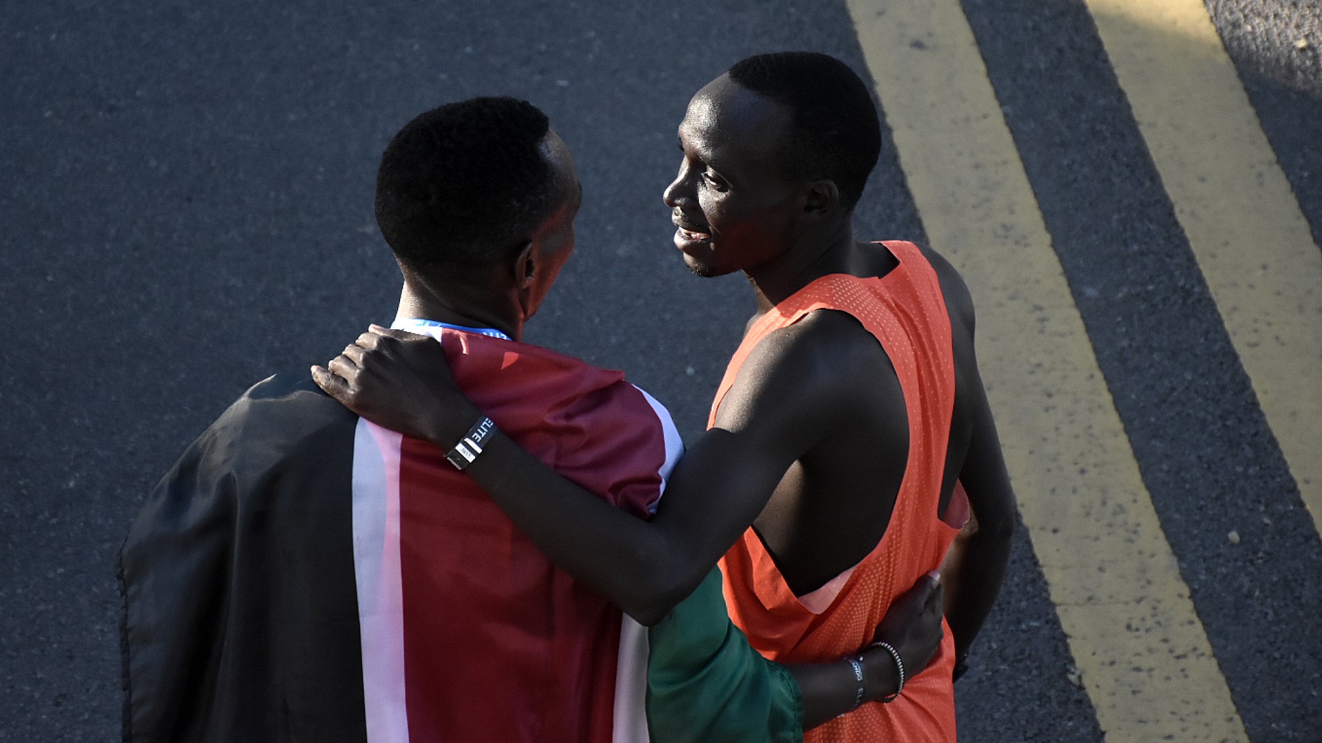 Cherono y Keroki se abrazan. Keroki, en segundo lugar, con una bandera al hombro