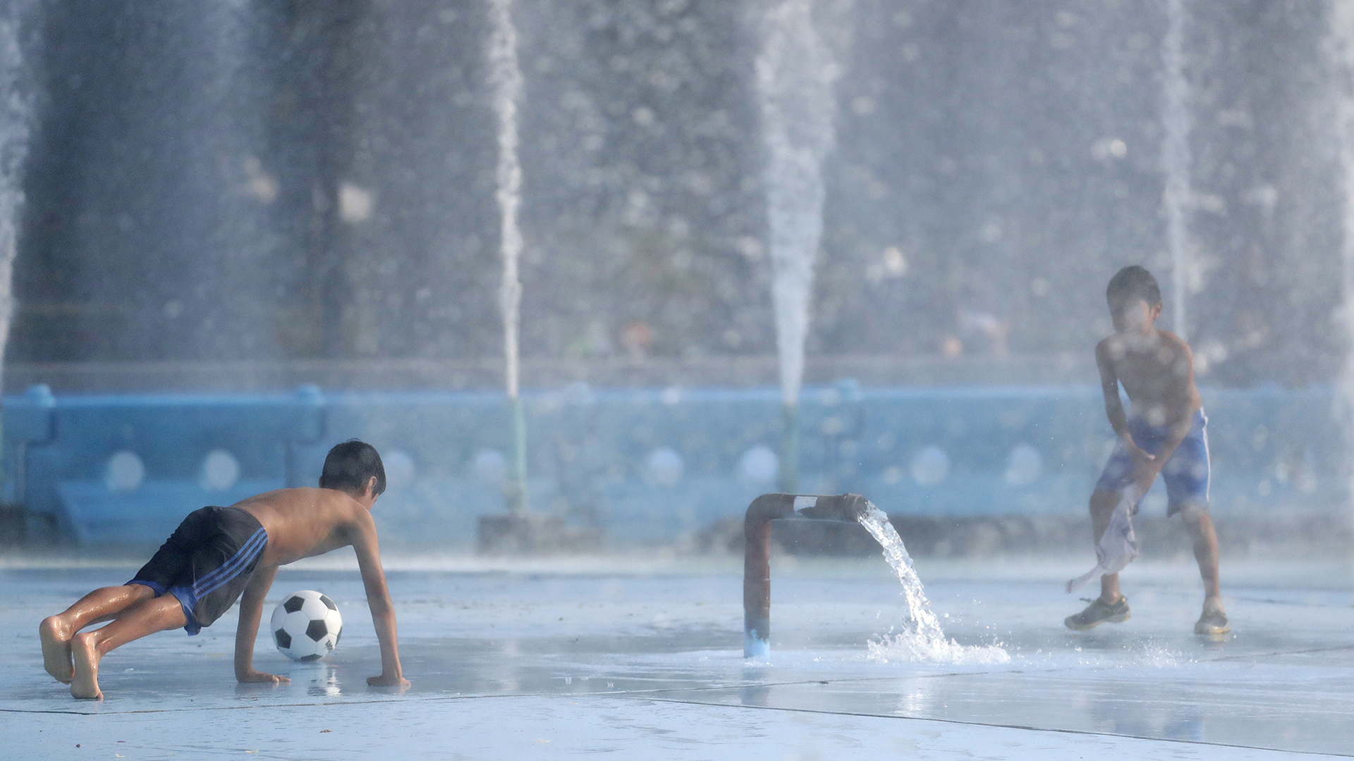 Los chicos combaten el calor jugando en el agua del Billie Jean King National Tennis Center