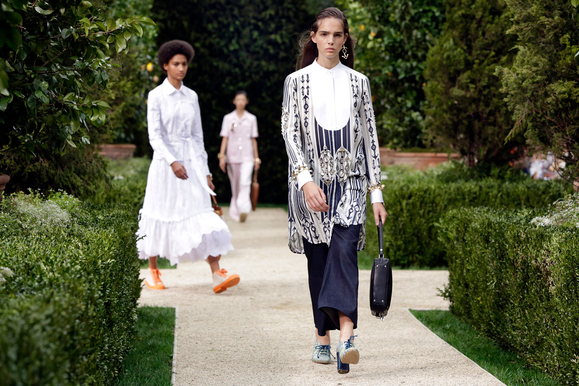 Los blancos y azules, dos tonalidades que nunca faltan en las pasarelas de Tory Burch, dos clásicos de la firma. En pasarela, una blusa estampada de mangas largas con un pantacourt de seda y botinetas acordonadas en degradés de azules