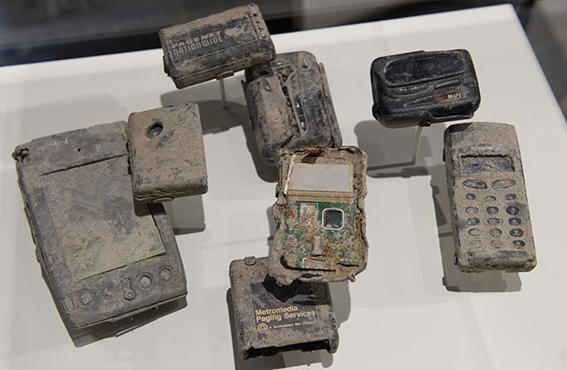 Teléfonos celulares, localizadores y dispositivos Palm Pilot calcinados y cubiertos de polvo