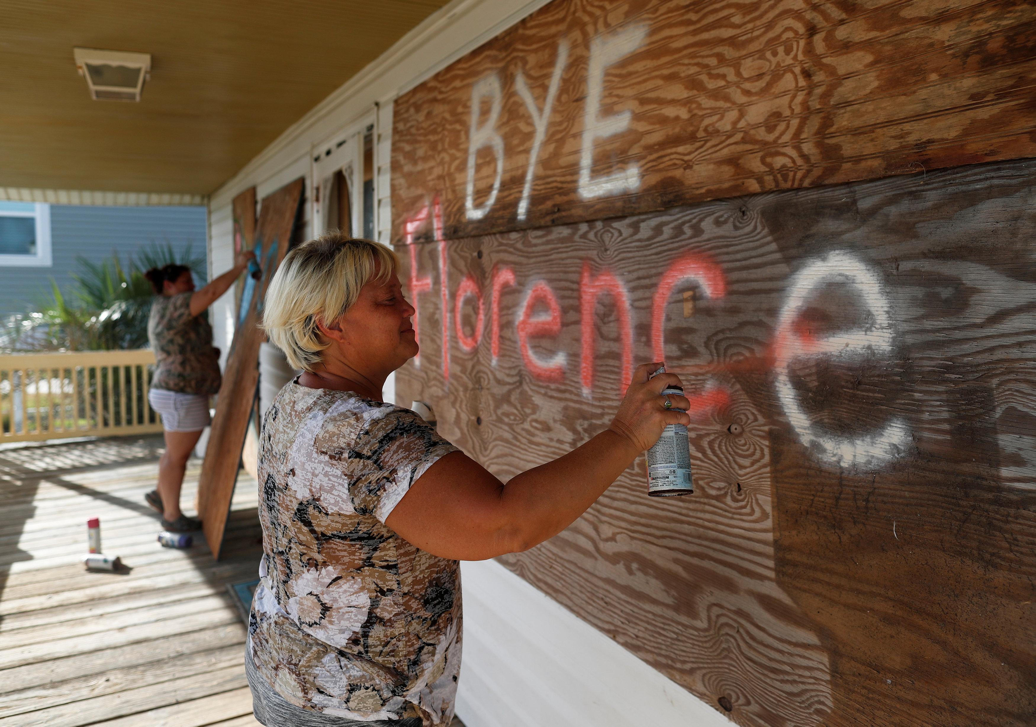 “Adiós, Florence”. Lisa Evers y su hija Amanda Hamilton, de Oak Island, decoran las tablas con las que protegieron su hogar como último paso antes de evacuar