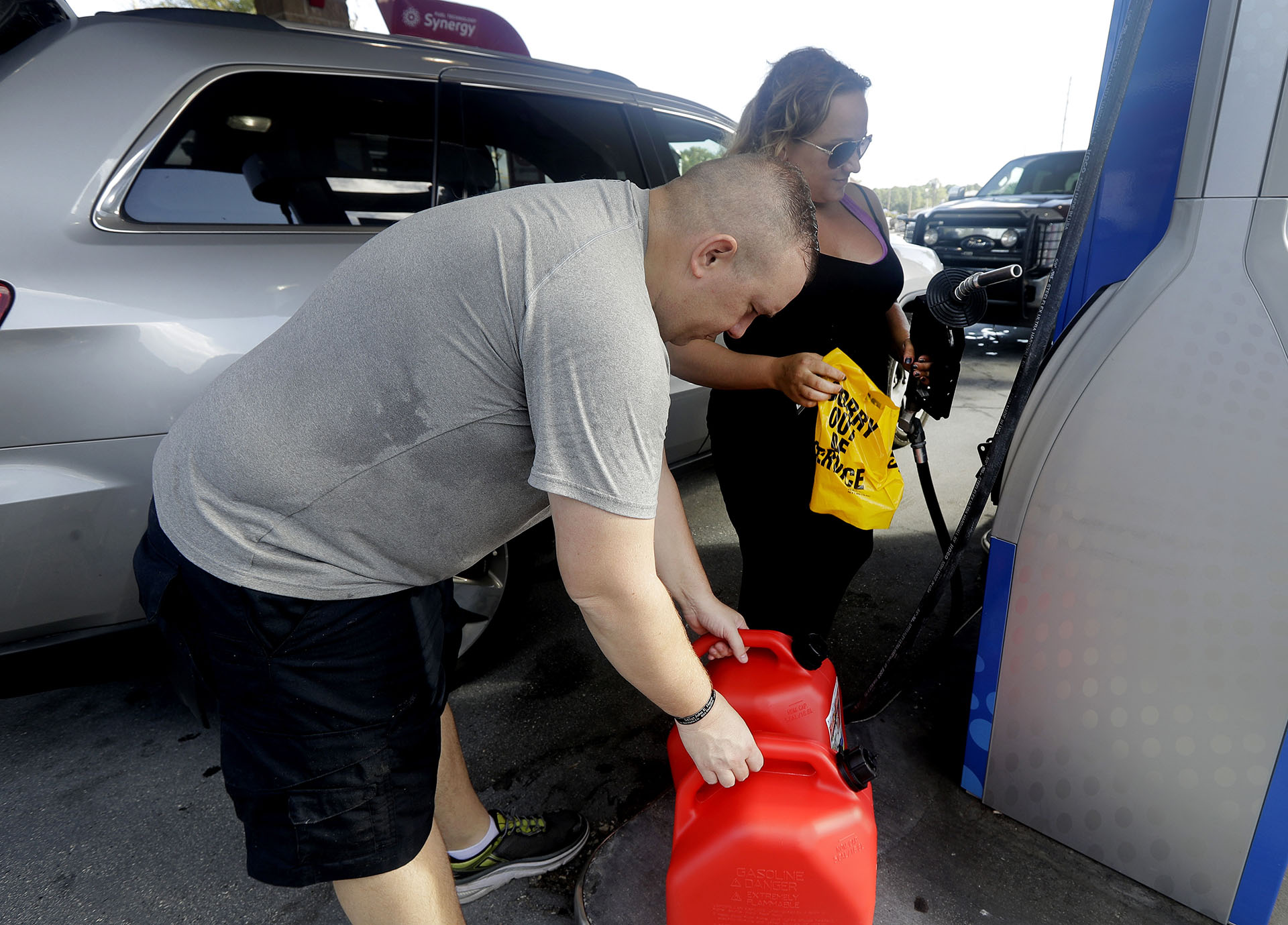 Sarah Dankanich saca un envoltorio “fuera de servicio” de una bomba de gasolina mientras su esposo, Bryan Dankanich, se prepara para cargar gasolina en latas antes del huracán Florence en Wilmington, Carolina del Norte (AP Photo/Chuck Burton)