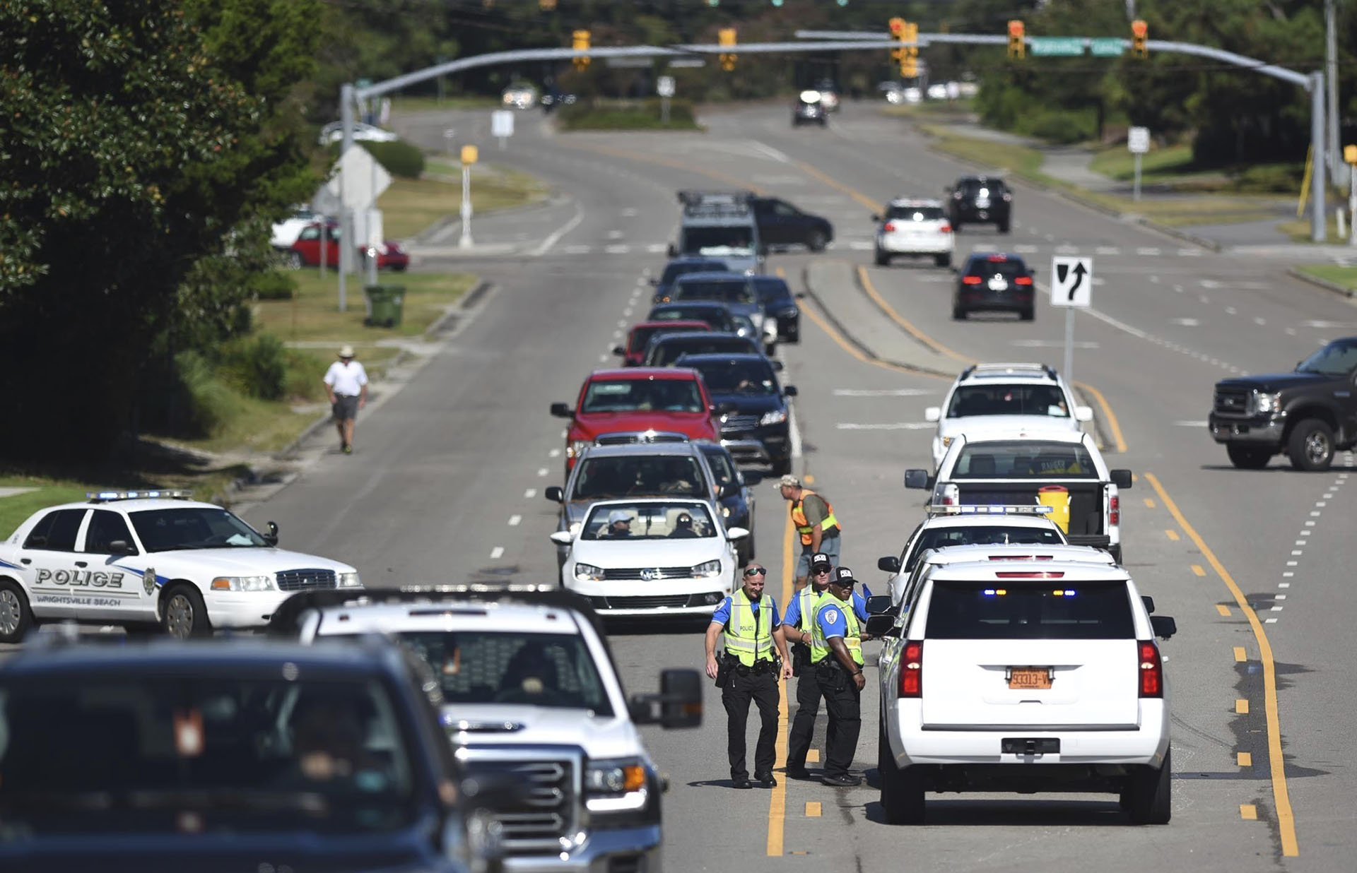 Los policías de Wrightsville Beach comprueban la identificación en el puente a Wrightsville Beach. Miles de personas tratan de huir del paso del huracán (Matt Born/The Star-News via AP)