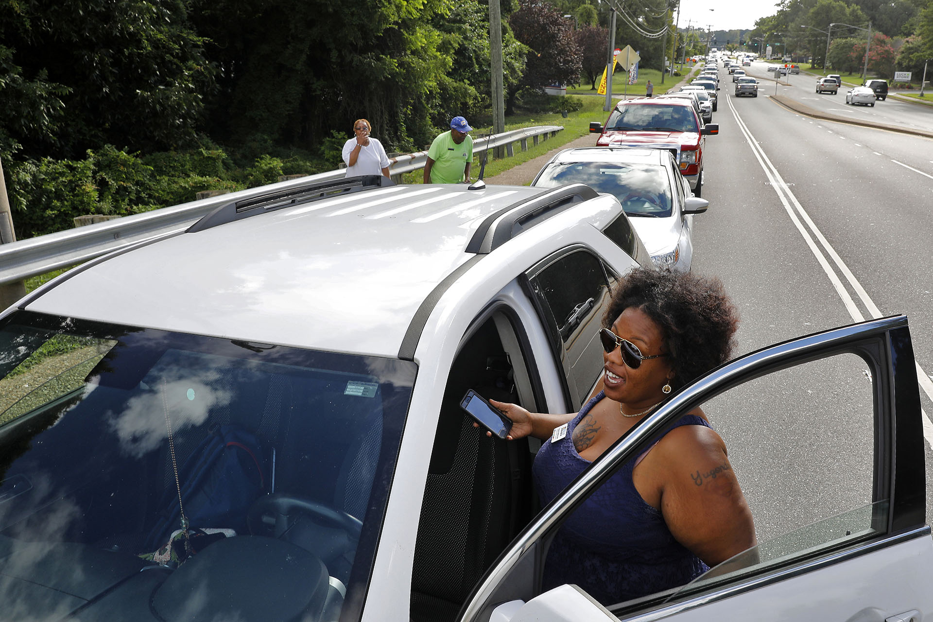 Yugonda Sample espera fuera de su automóvil en una fila de autos a lo largo de Oyster Point Road mientras la gente espera recoger sacos de arena. La ciudad de Newport News ofrecía sacos de arena gratis a los residentes en el Centro de Operaciones de Obras Públicas a medida que se aproxima el huracán Florence (Jonathon Gruenke/The Daily Press via AP)