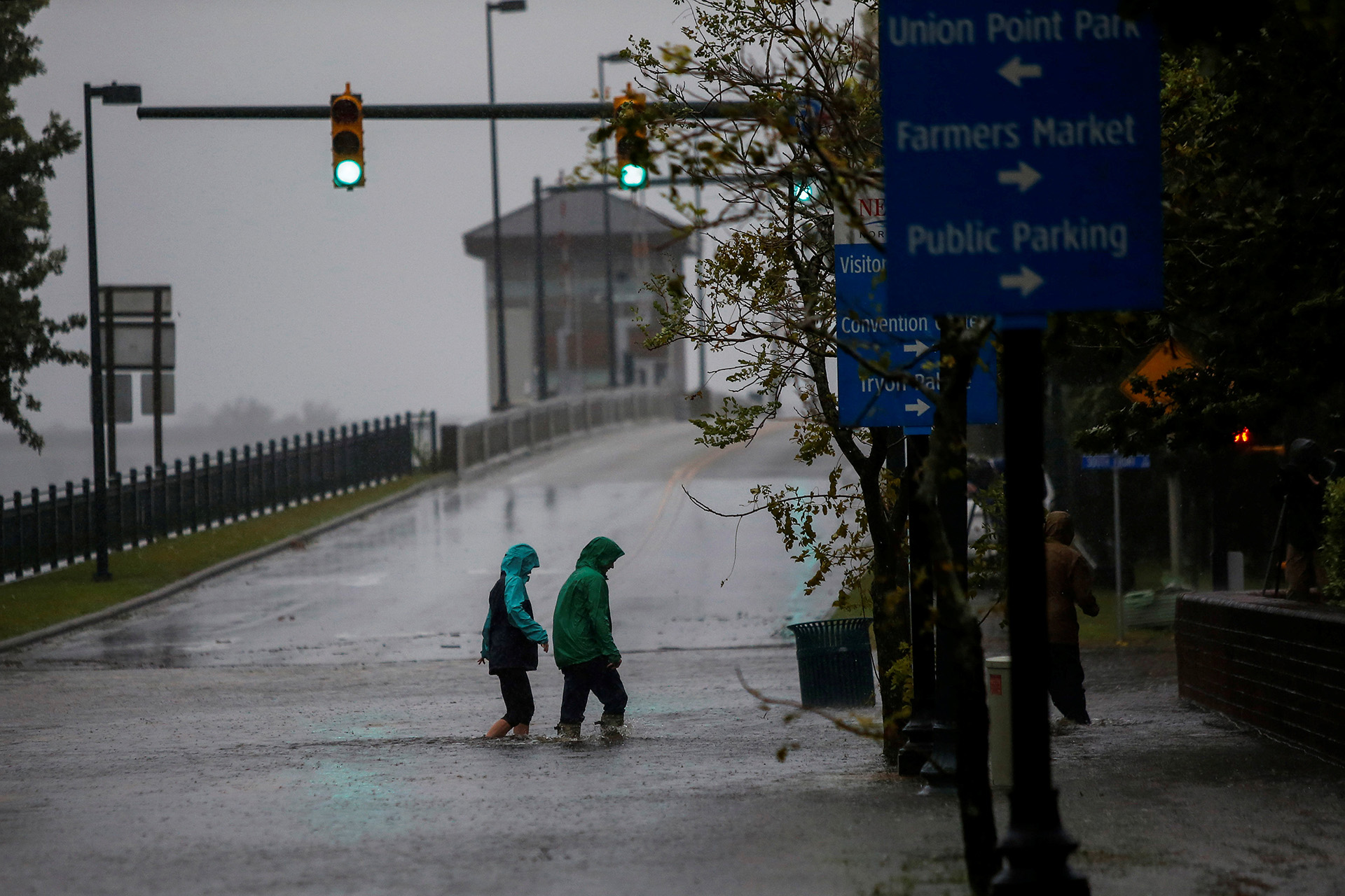 Dos personas cruzan una avenida abajo de una lluvia torrencial.