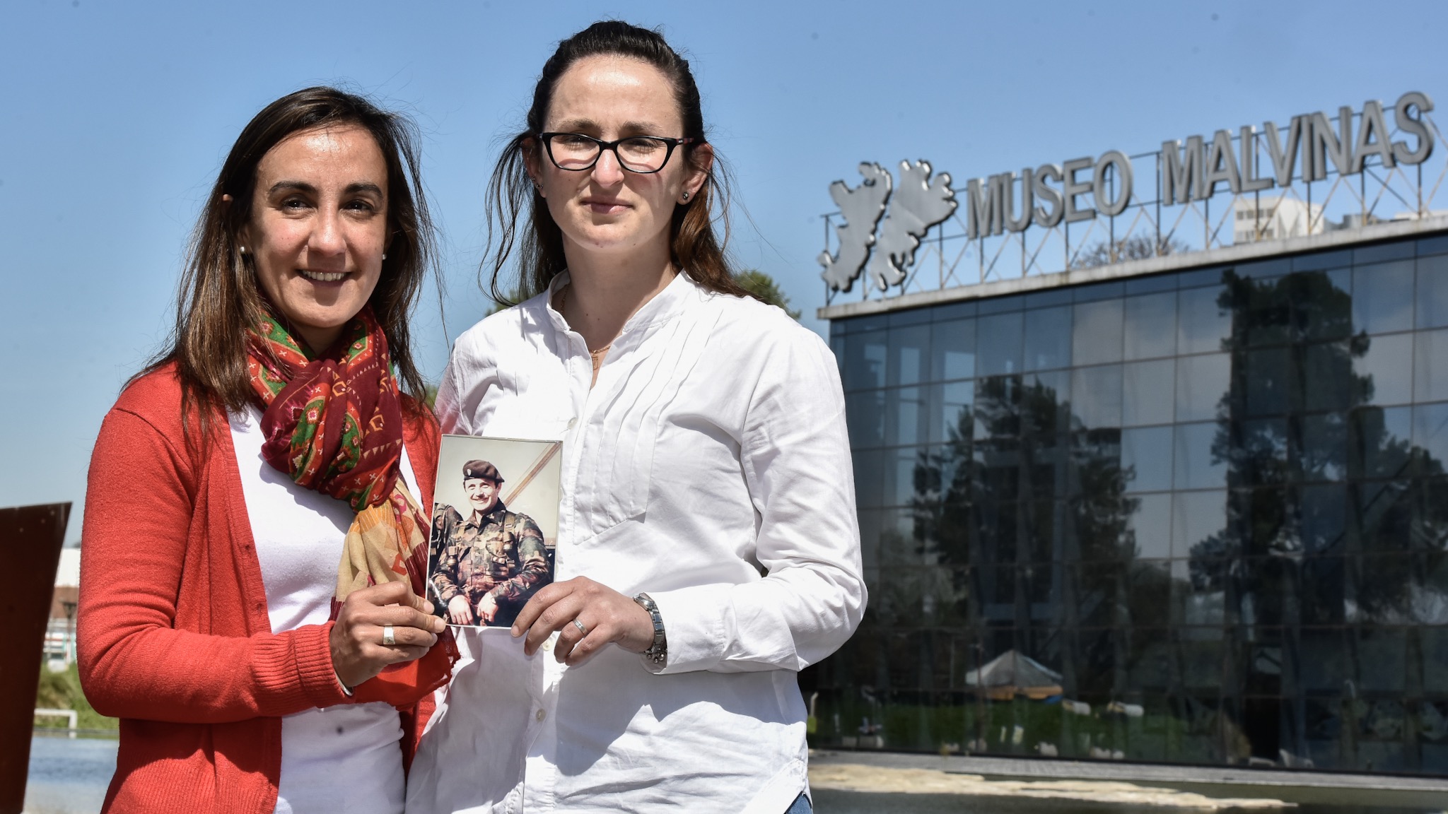 Lorna y Victoria, sobrinas del capitán Márquez frente al Museo Malvinas con la foto de su tío (Adrián Escandar)