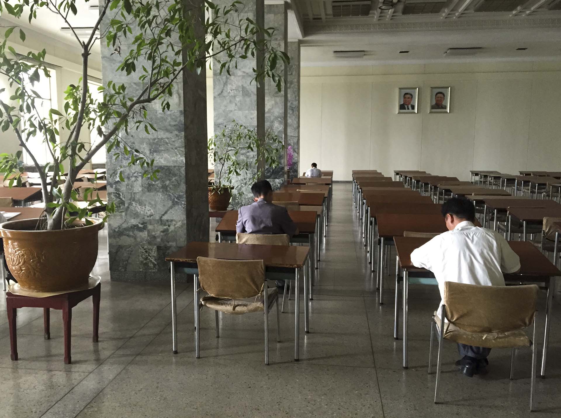 En la Gran Casa de Estudios del Pueblo, que oficia de biblioteca central de Pyongyang y es uno de los pocos edificios públicos en los que un extranjero puede ver las computadoras con acceso a la intranet norcoreana aunque no pueda usarlas, tomamos el ascensor de madera hasta el segundo piso, donde estaba la sala de lectura, una habitación presidida, como todas en aquel lugar, por los retratos de los dos Kim