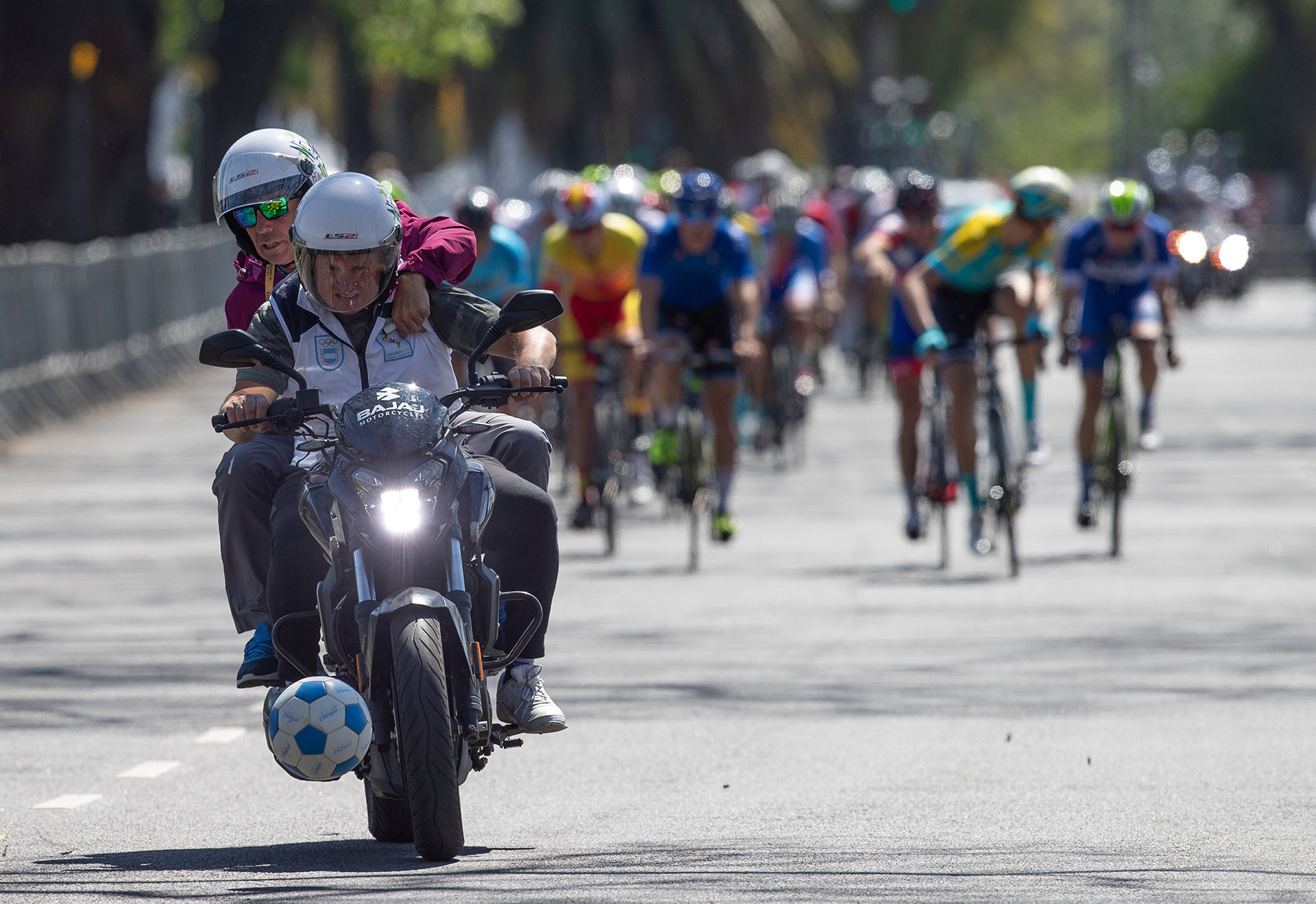 Un voluntario de la organización precede en moto la carrera de ciclismo masculino en busca de quitar de la pista un balón que apareció repentinamente ( REUTERS)