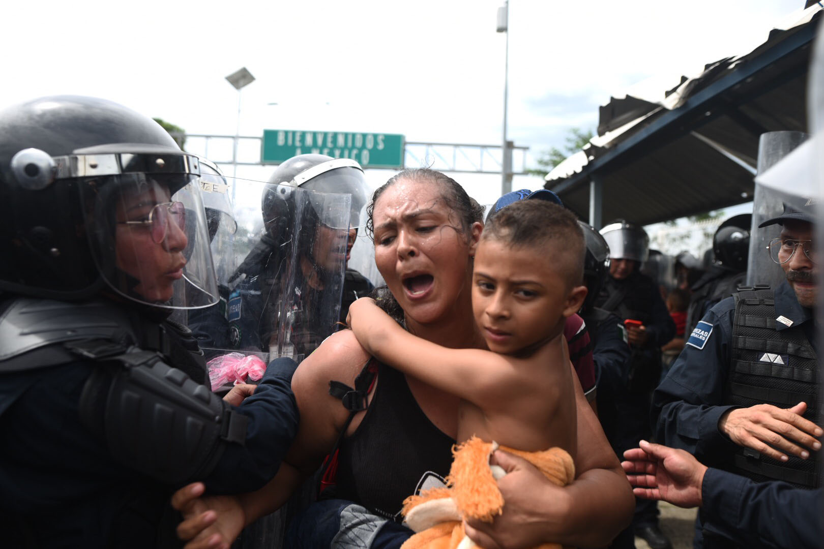 Miembros de la policía mexicana le impiden el pase a una migrante hondureña con su hijo en el paso fronterizo entre Guatemala y México. (EFE/Edwin Bercían)