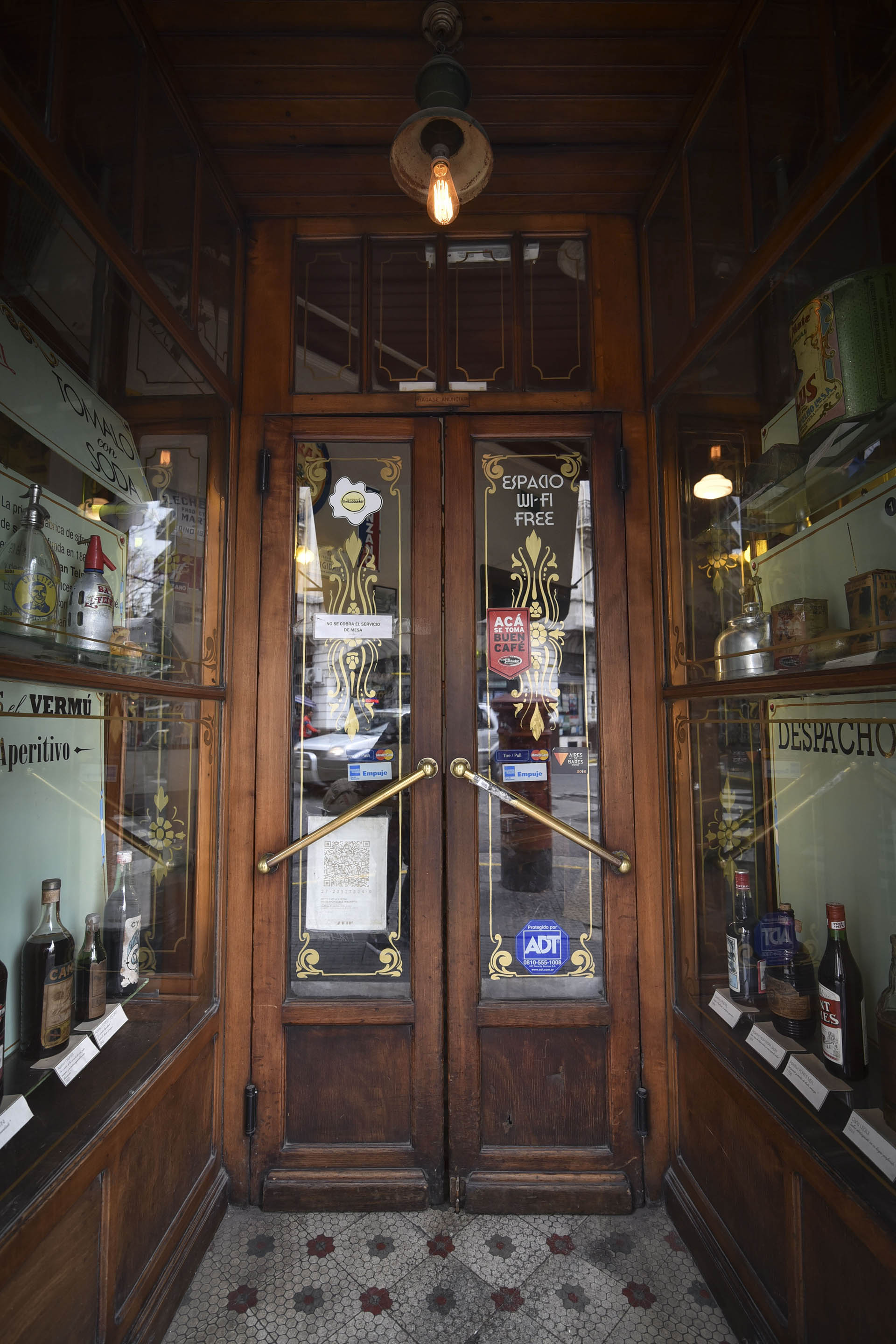 Sus puertas de madera con manijas de acero. Decoraciones de botellones con años de antigüedad y grandes historias detrás. Sigue manteniendo la fachada, sus ventanales y puertas originales