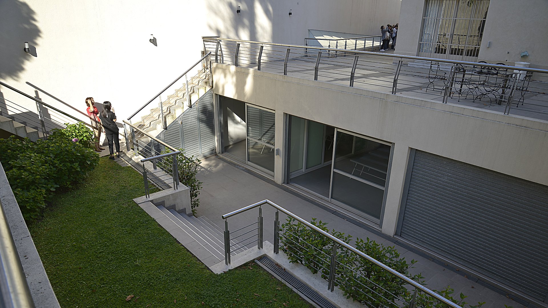 El jardín del interior de la casa. Escaleras y ventanales de vidrio. Una fachada interna moderna