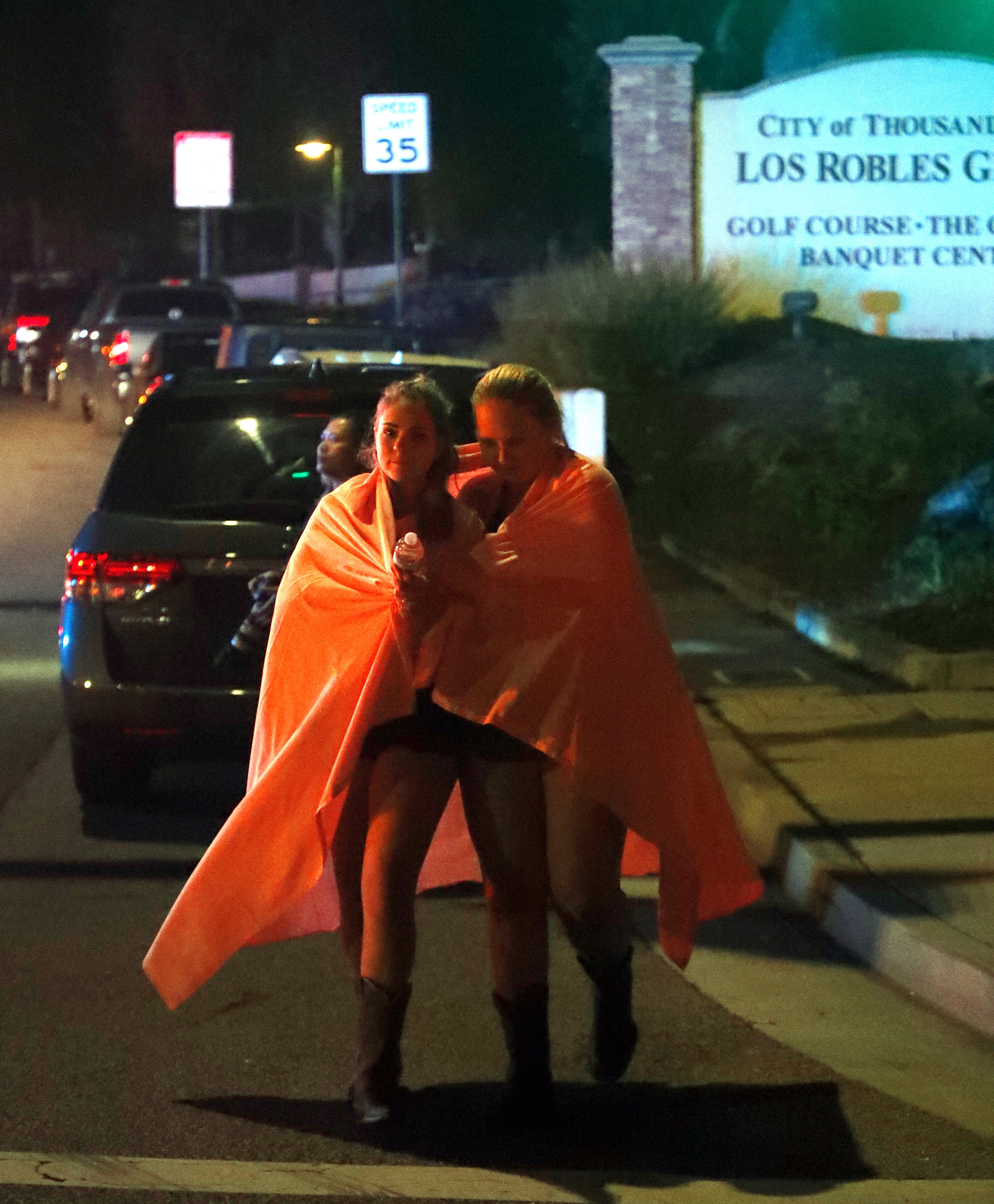 Dos mujeres envueltas en una sábana abandonan el área del tiroteo