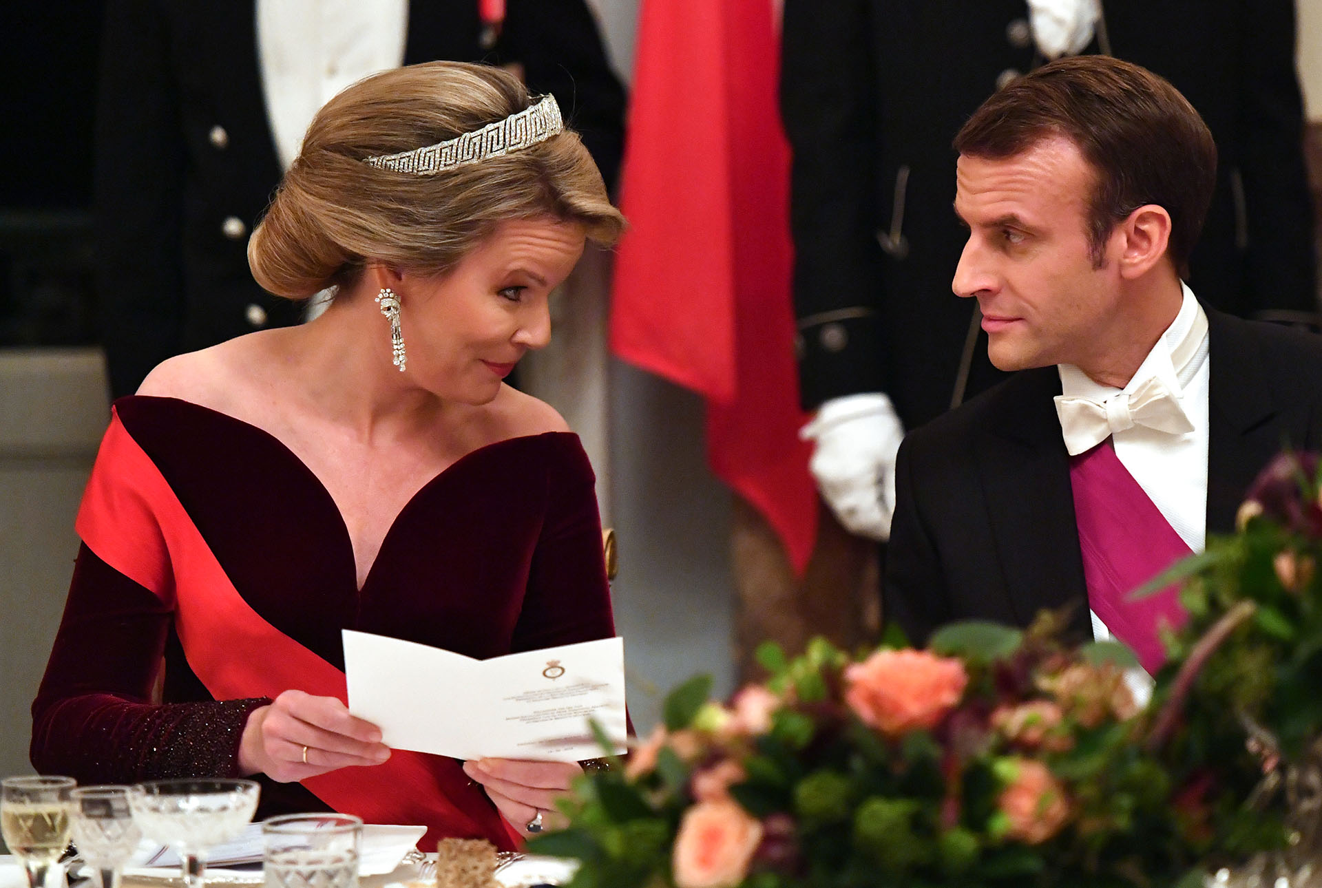La reina Mathilde conversa con el presidente francés, Emmanuel Macron, en la mesa principal