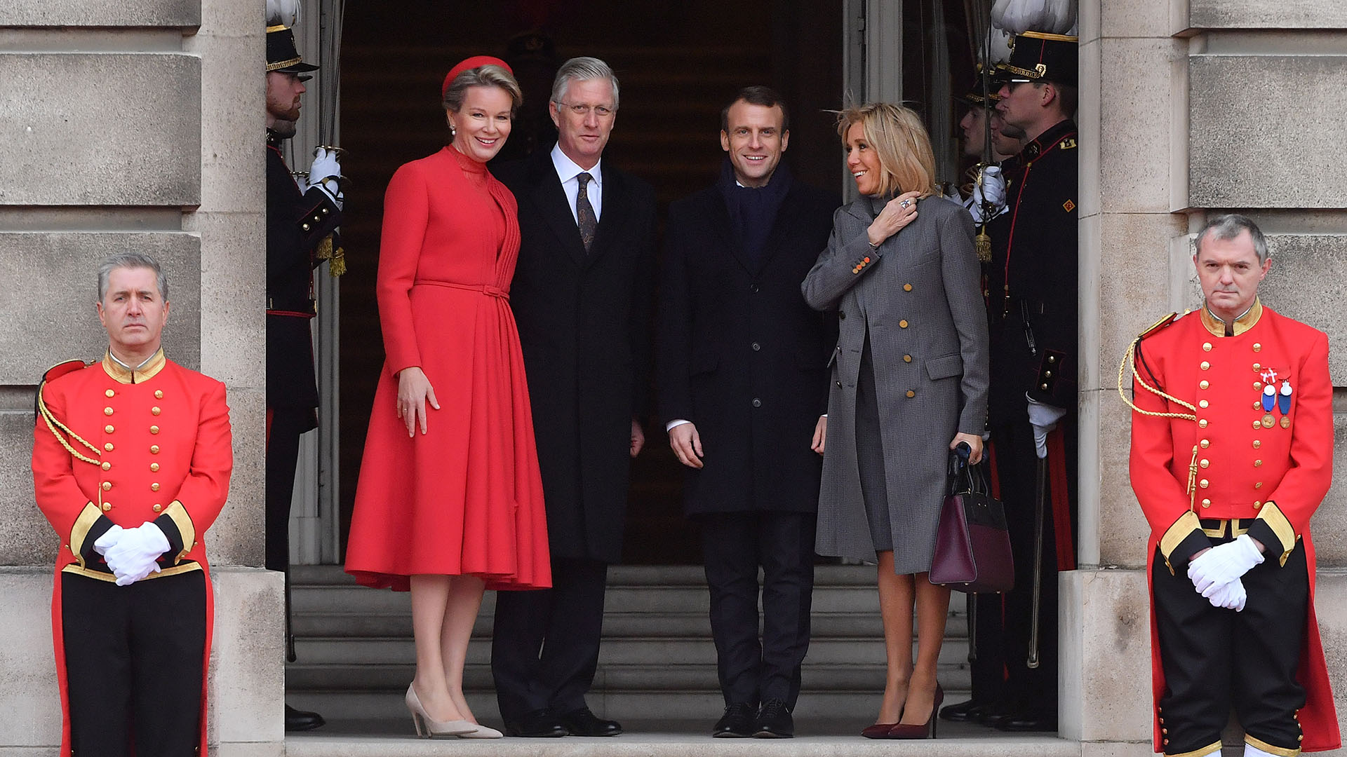 Mathilde de Bélgica eligió un vestido colorado, que combinó con su tapado y su tocado. La reina eligió stilettos y cartera “nude”