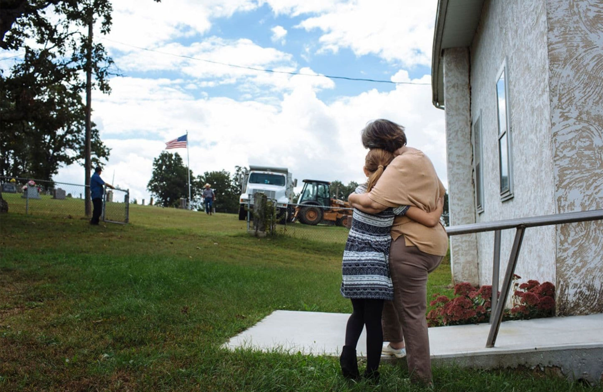Raeleigh y su bisabuela materna, Patsy May, de 65 años, se consuelan mientras se cava una tumba antes del funeral de Raleigh. Había solicitado ser enterrado bajo el asta de la bandera en el cementerio detrás de su iglesia en Hartville, Missouri (Angus Mordant/The Washington Post)