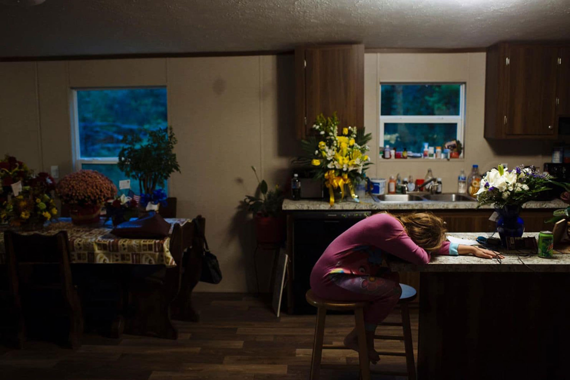 Raeleigh apoya la cabeza en el mostrador de la cocina de su bisabuela la mañana después del funeral de su bisabuelo. Temía regresar a la escuela tras tomarse varios días de descanso por la muerte (Angus Mordant/The Washington Post)