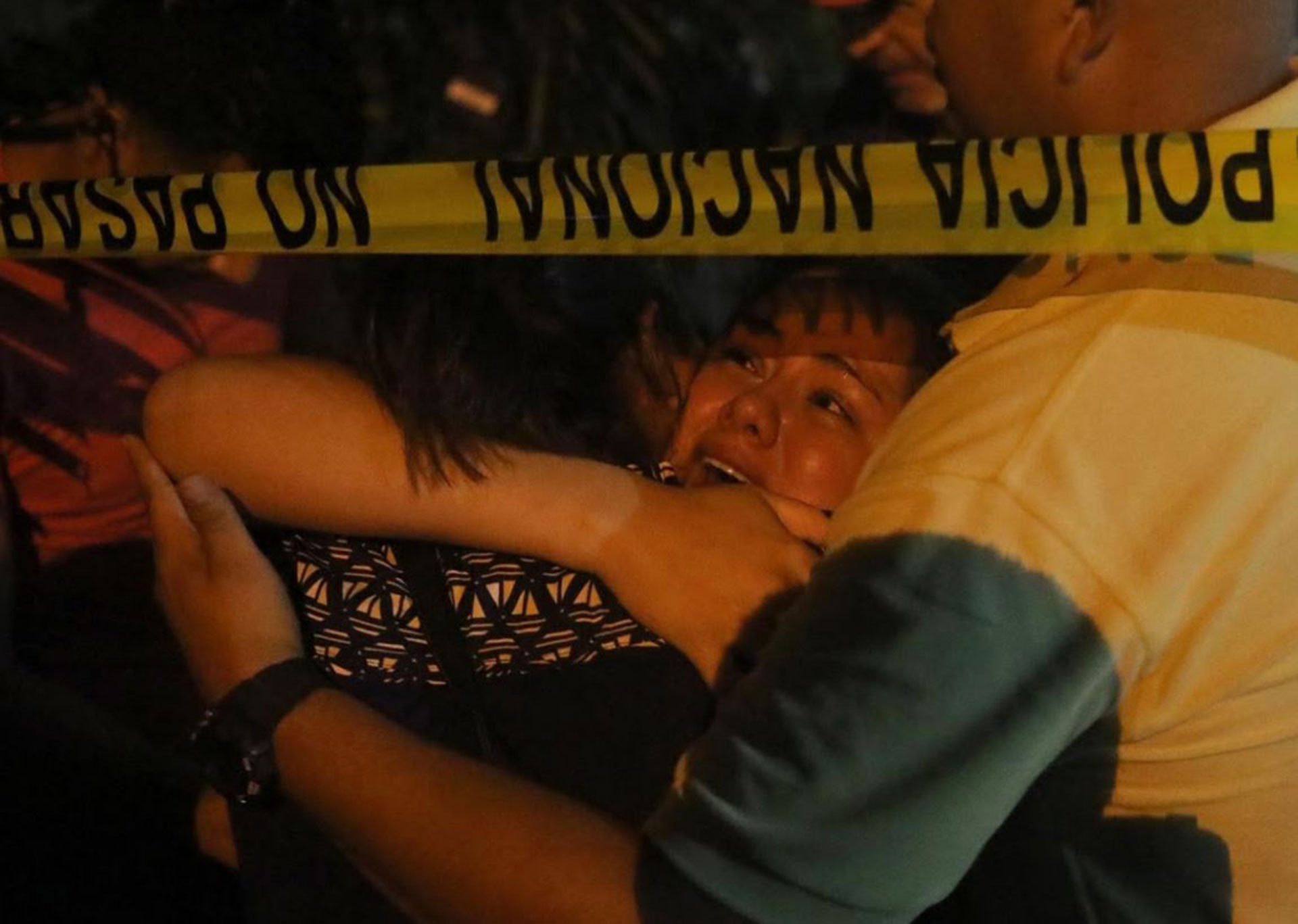 Una mujer llora en la escena del crimen después de que dos hombres fueron asesinados por la violencia entre pandillas