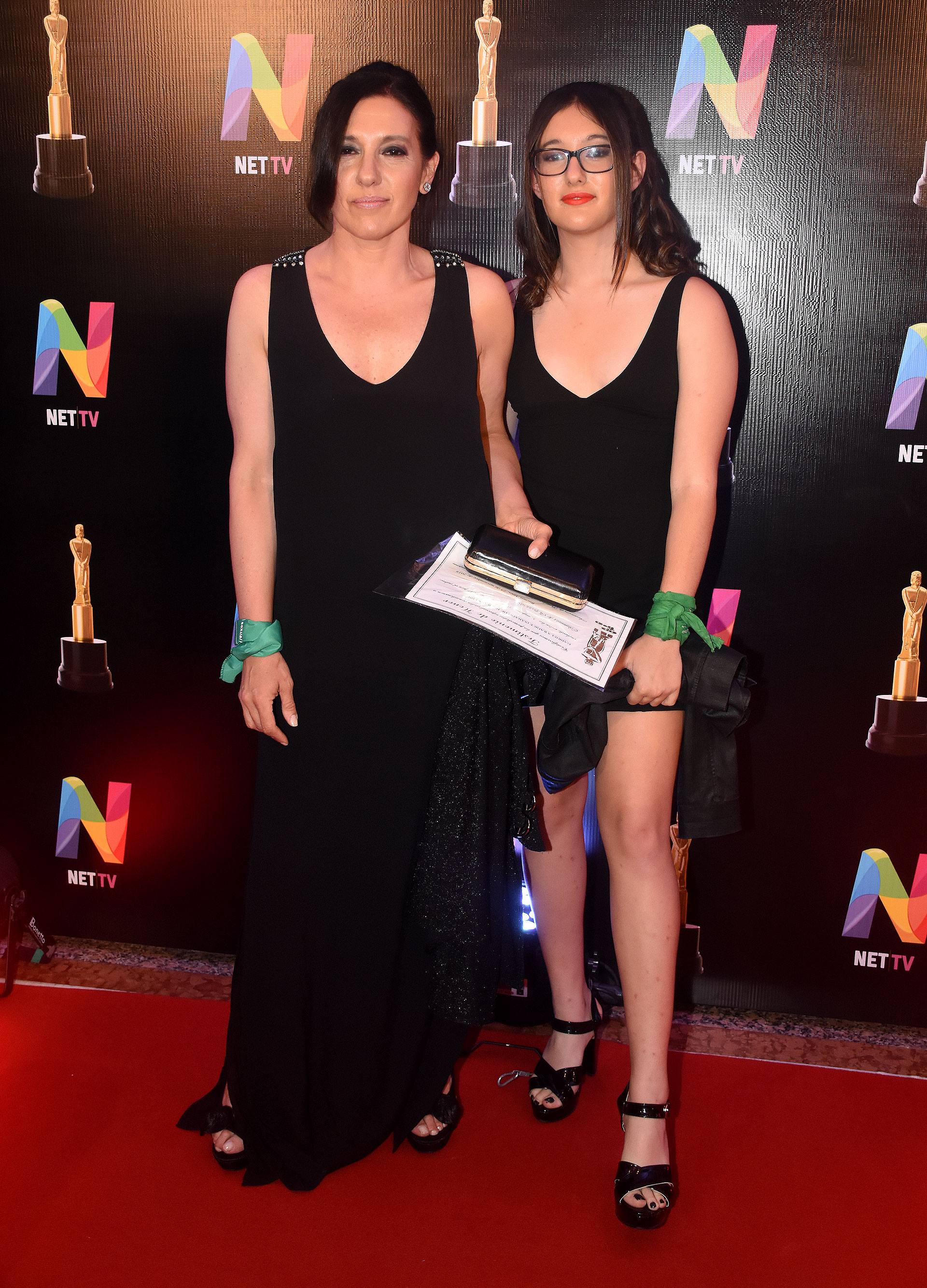 Gabriela Radice y su hija. Ambas lucieron looks total black. La periodista un vestido largo sin mangas y sandalias a tono. Su hija, vestido corto y sandalias. ¿El detalle? Ambas lucieron en sus muñecas el pañuelo verde