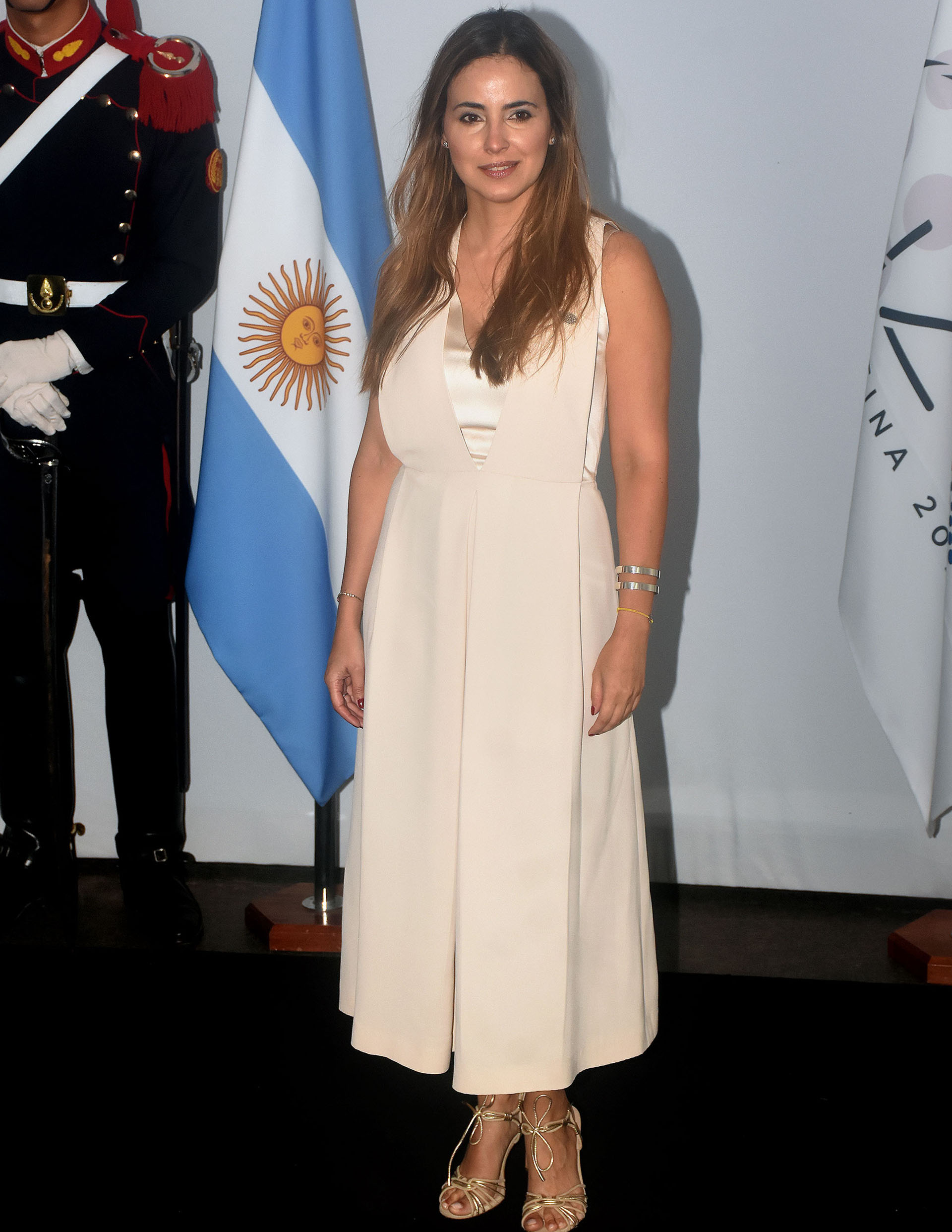 María Gabriela Sigala, del Banco Interamericano de Desarrollo (BID), eligió un vestido sin mangas, gran escote V y combinación de dos géneros: seda natural y raso. Ambos en tonalidades beige. Completó su look con sandalias doradas y esclavas a tono