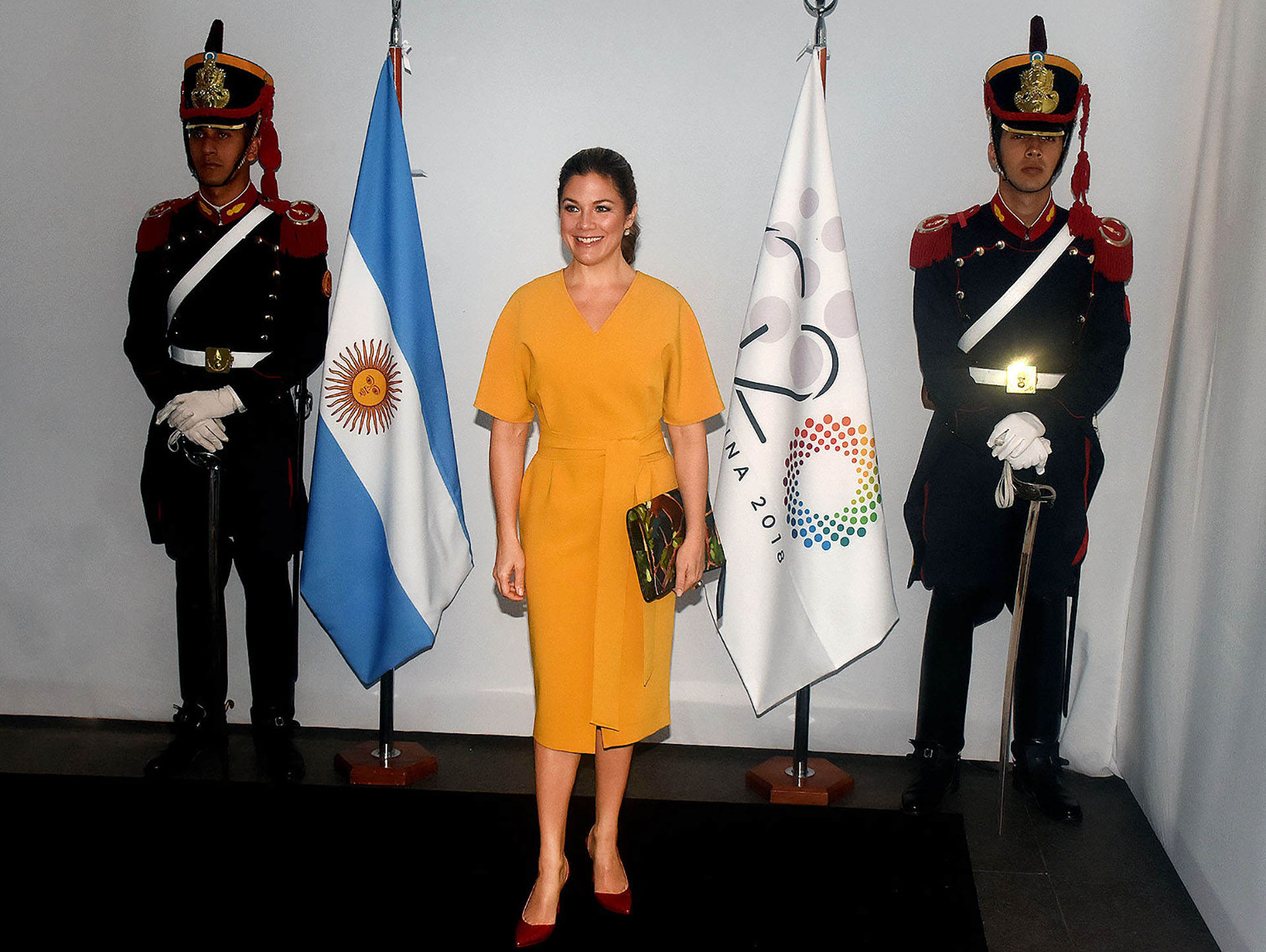 Sophie Trudeau, la mujer del primer ministro de Canadá, escogió un vestido estilo japonés en color mostaza. Con escote V, mangas amplias y un gran lazo a la cintura. Completó su look con un sobre multicolor y stilettos en punta y taco chupete en rojo acharolado