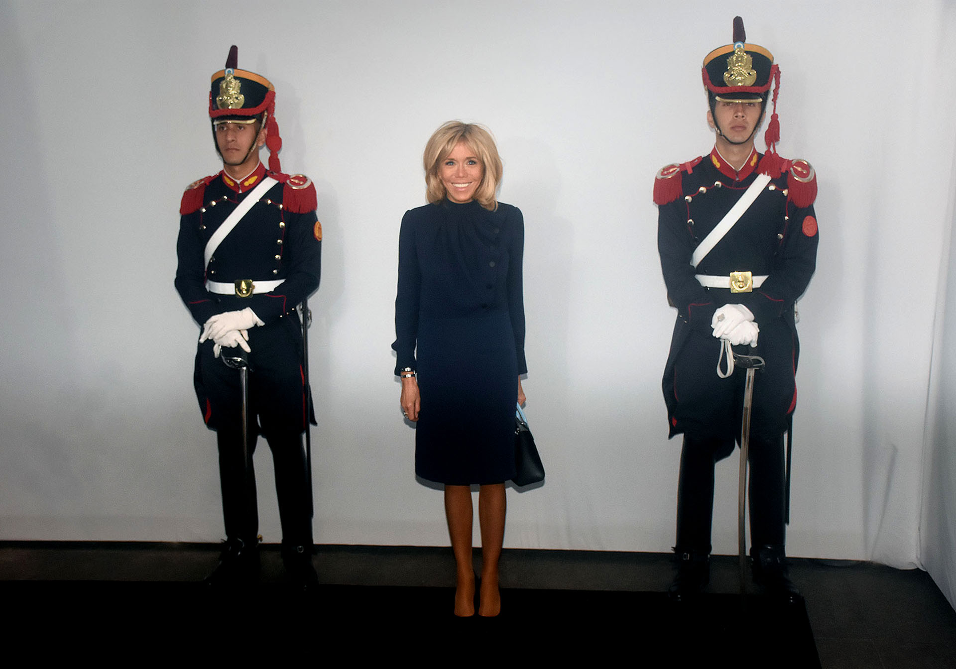 Brigitte Macron, una de las últimas en llegar al Malba, volvió a elegir un conjunto de dos piezas azul noche -el “nuevo negro” en la moda-. Una blusa con jabot y botones a tono y la falda pencil que tanto caracteriza a la primera dama francesa. Completó su look con una mini bag y zapatos a tono. El beauty look, al igual que siempre, su cabello bob y make up sobrio