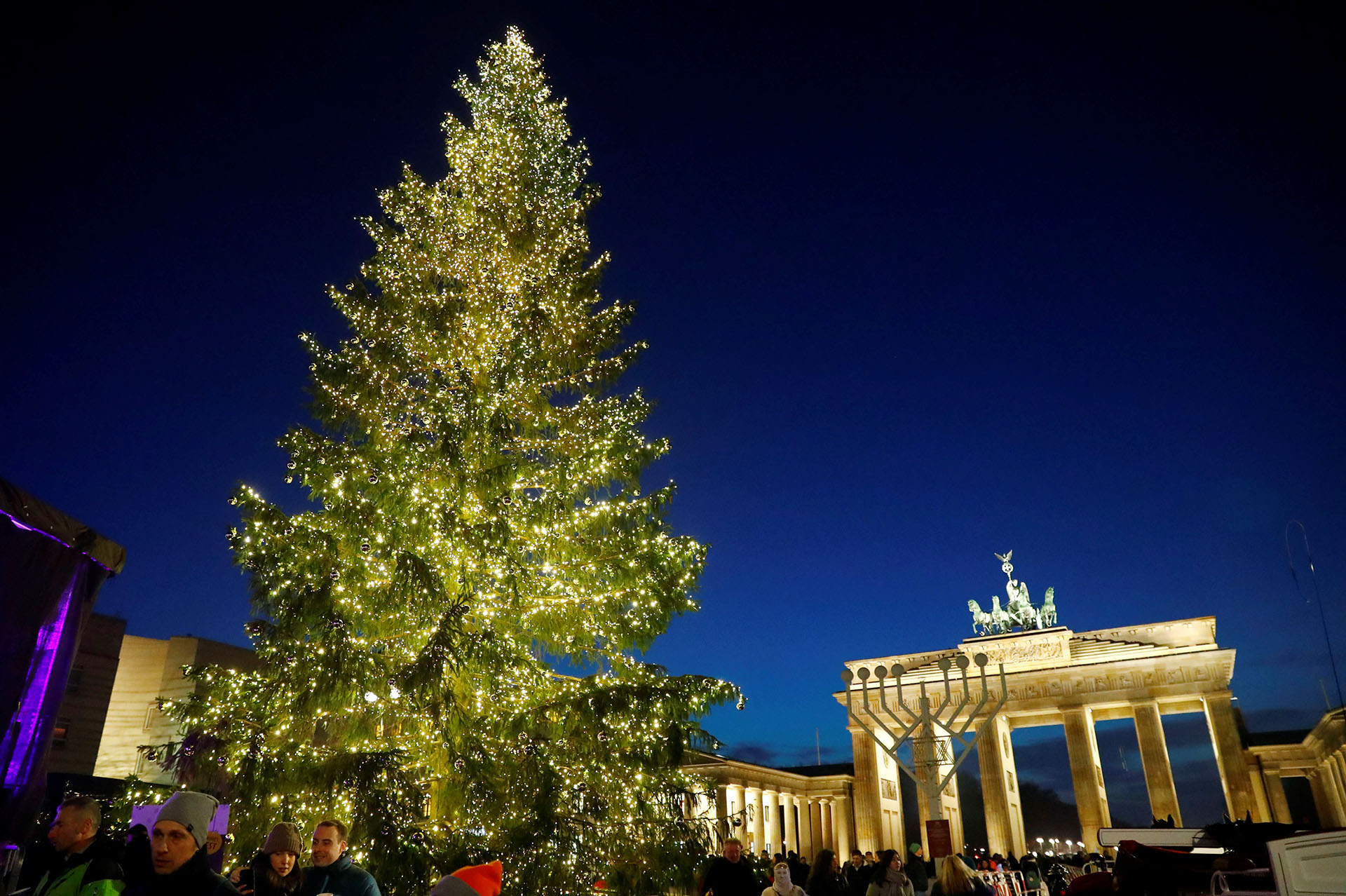 BERLÍN, ALEMANIA. En el boulevard Unter den Linden está iluminado el árbol alemán. Detrás, La Puerta Brandenburg en Berlín