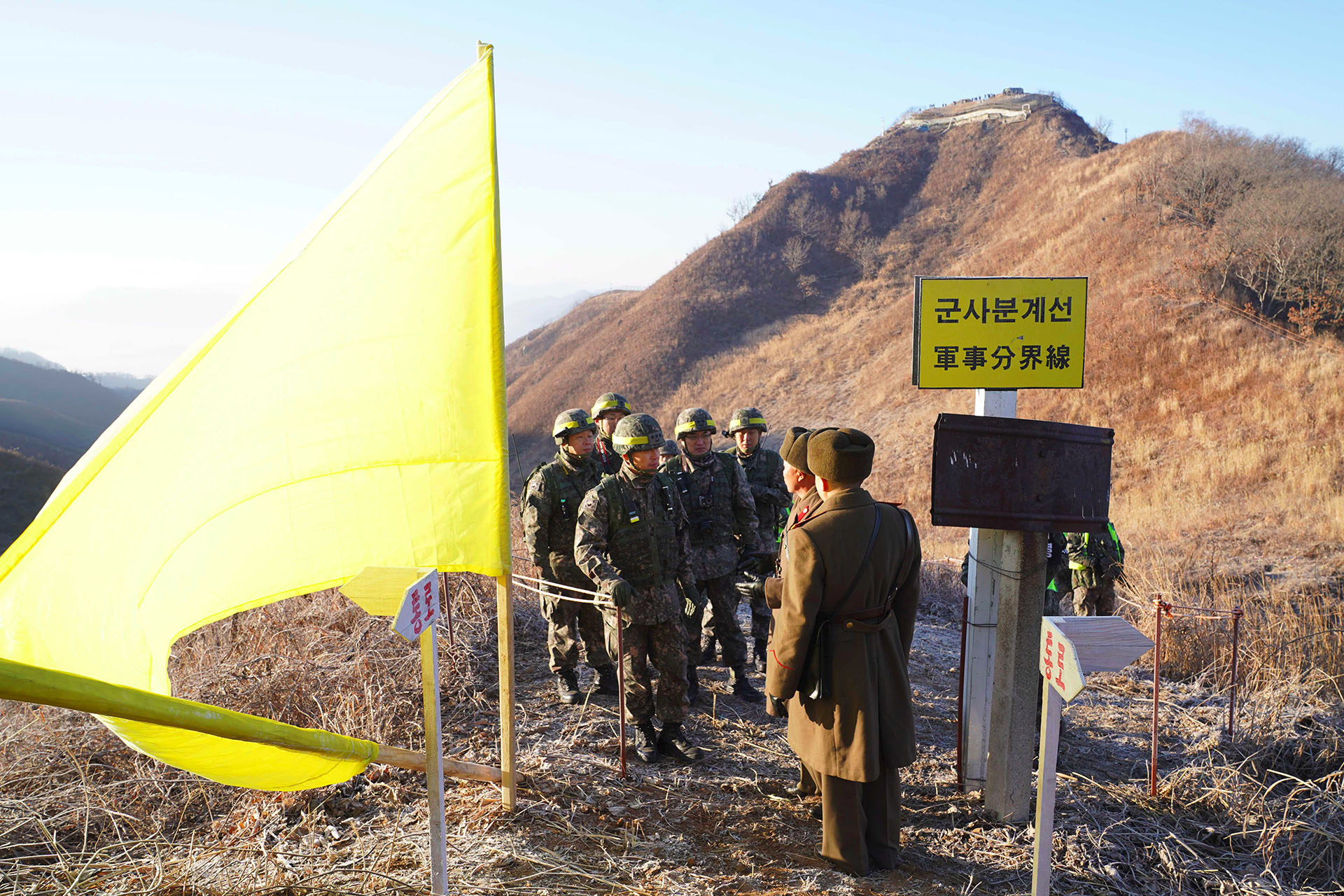Soldado surcoreano (der.) estrechando la mano de un soldado norcoreano (izq.) antes de cruzar la Línea de Demarcación Militar para inspeccionar el puesto de guardia norcoreano desmantelado dentro de la zona desmilitarizada (DMZ) que divide las dos Coreas en Cheorwon. (AFP)