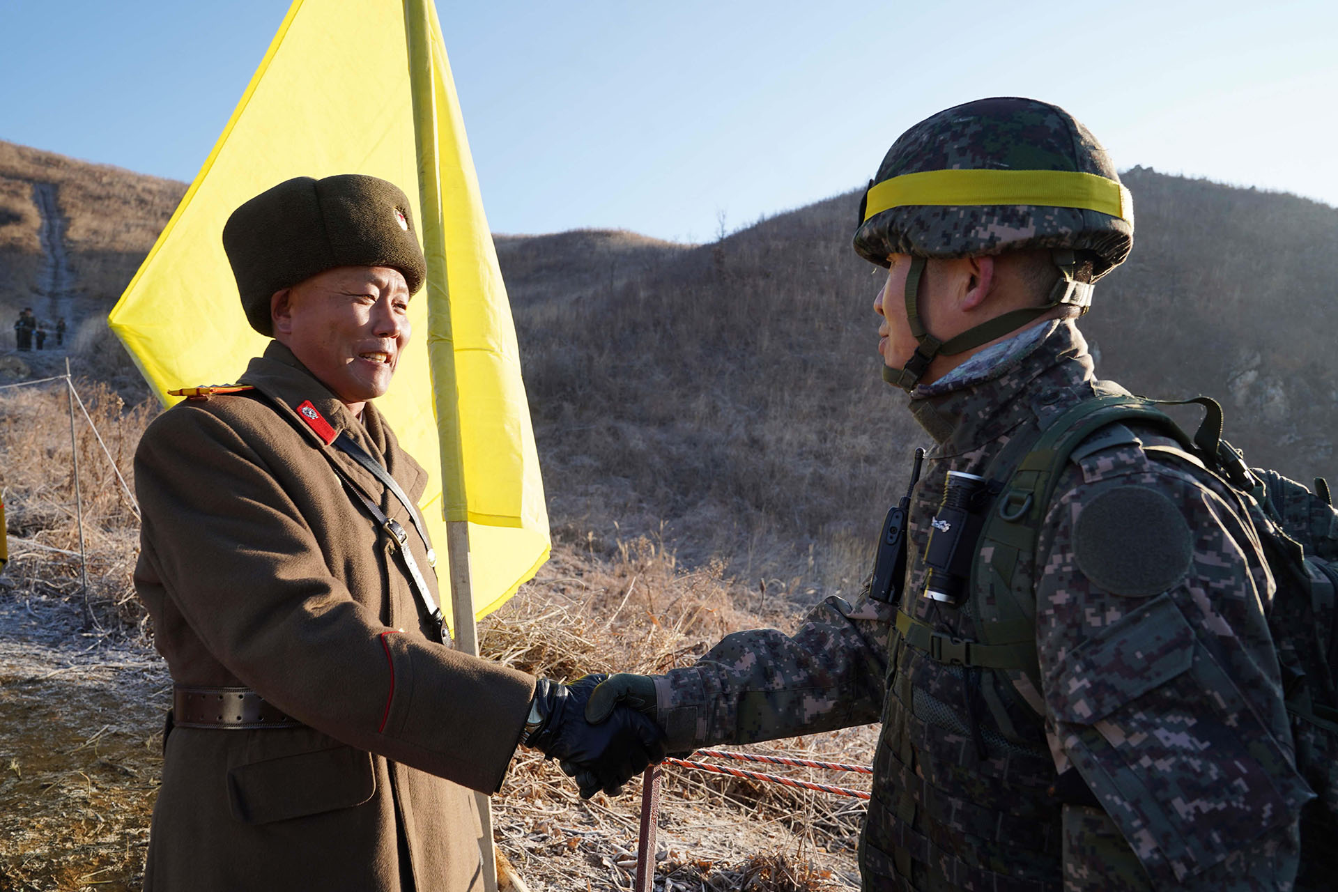 Soldado surcoreano (der.) estrechando la mano de un soldado norcoreano (izq.) antes de cruzar la Línea de Demarcación Militar para inspeccionar el puesto de guardia norcoreano desmantelado dentro de la zona desmilitarizada (DMZ) que divide las dos Coreas en Cheorwon. (AFP)