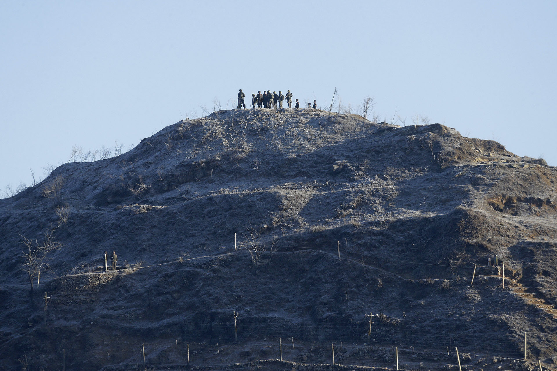 Soldados del ejército de Corea del Sur (con cintas amarillas en la cabeza) y sus homólogos de Corea del Norte inspeccionan el desmantelado puesto de guardia de Corea del Norte dentro de la Zona Desmilitarizada (DMZ) en la sección central de la frontera intercoreana en Cheorwon, Corea del Sur, el 12 de diciembre de 2018. (AFP)