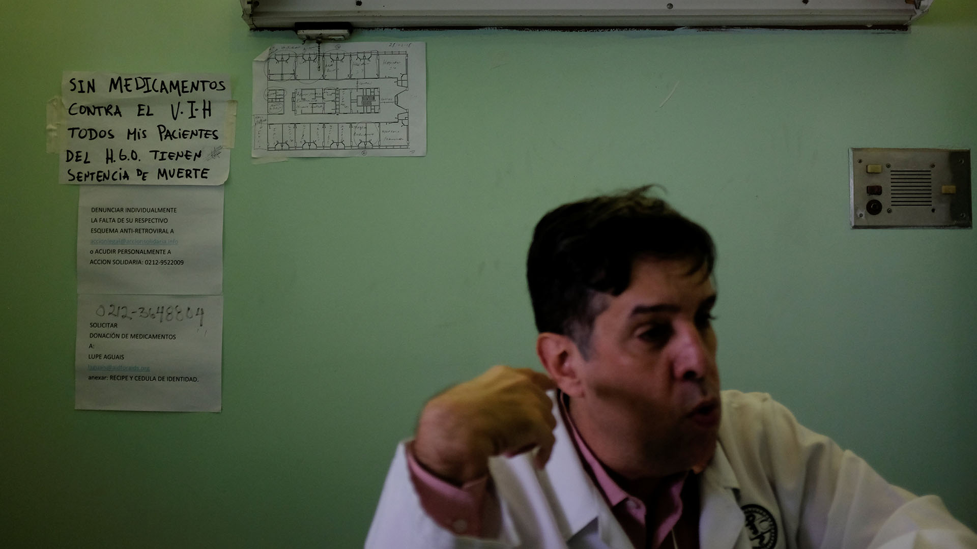 Un cartel que dice “Sin medicamentos contra el VIH, todos mis pacientes en el hospital tienen una sentencia de muerte”, se ve detrás del doctor Carlos Pérez durante una entrevista con Reuters en el hospital José Gregorio Hernández en el barrio de Catia en Caracas
