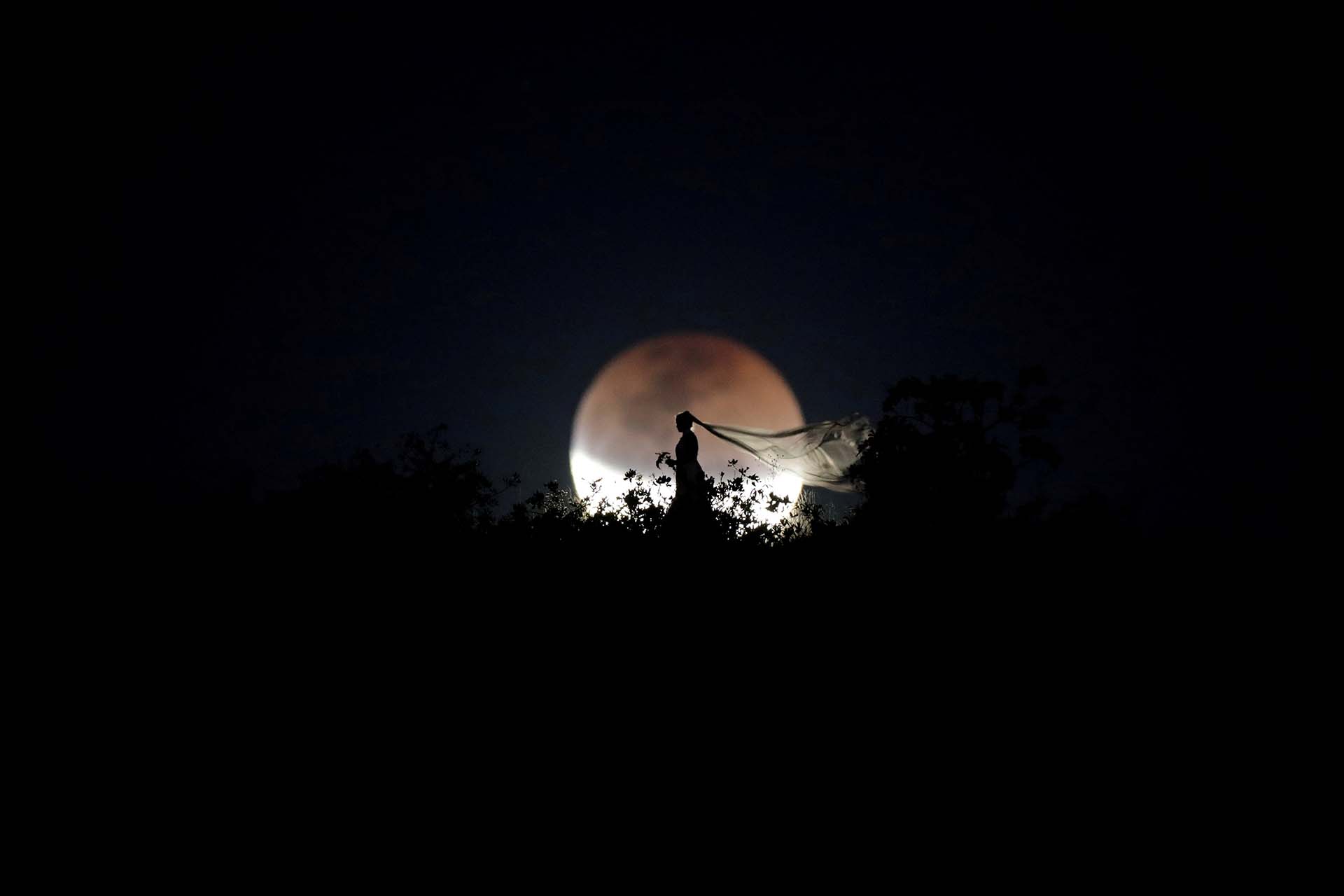 Una novia posa para una foto durante un eclipse lunar total en Brasilia, Brasil, el 27 de julio