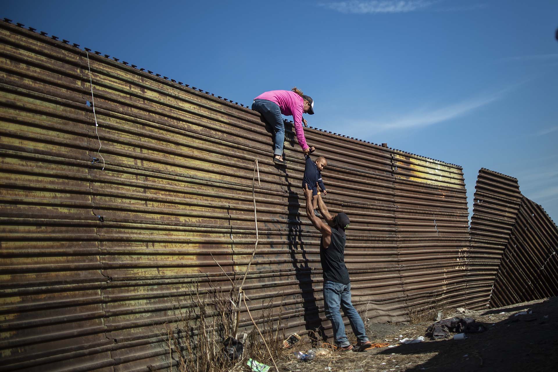 Un grupo de migrantes centroamericanos trepa la valla fronteriza entre México y EEUU cerca del paso fronterizo de El Chaparral, en Tijuana, el 25 de noviembre