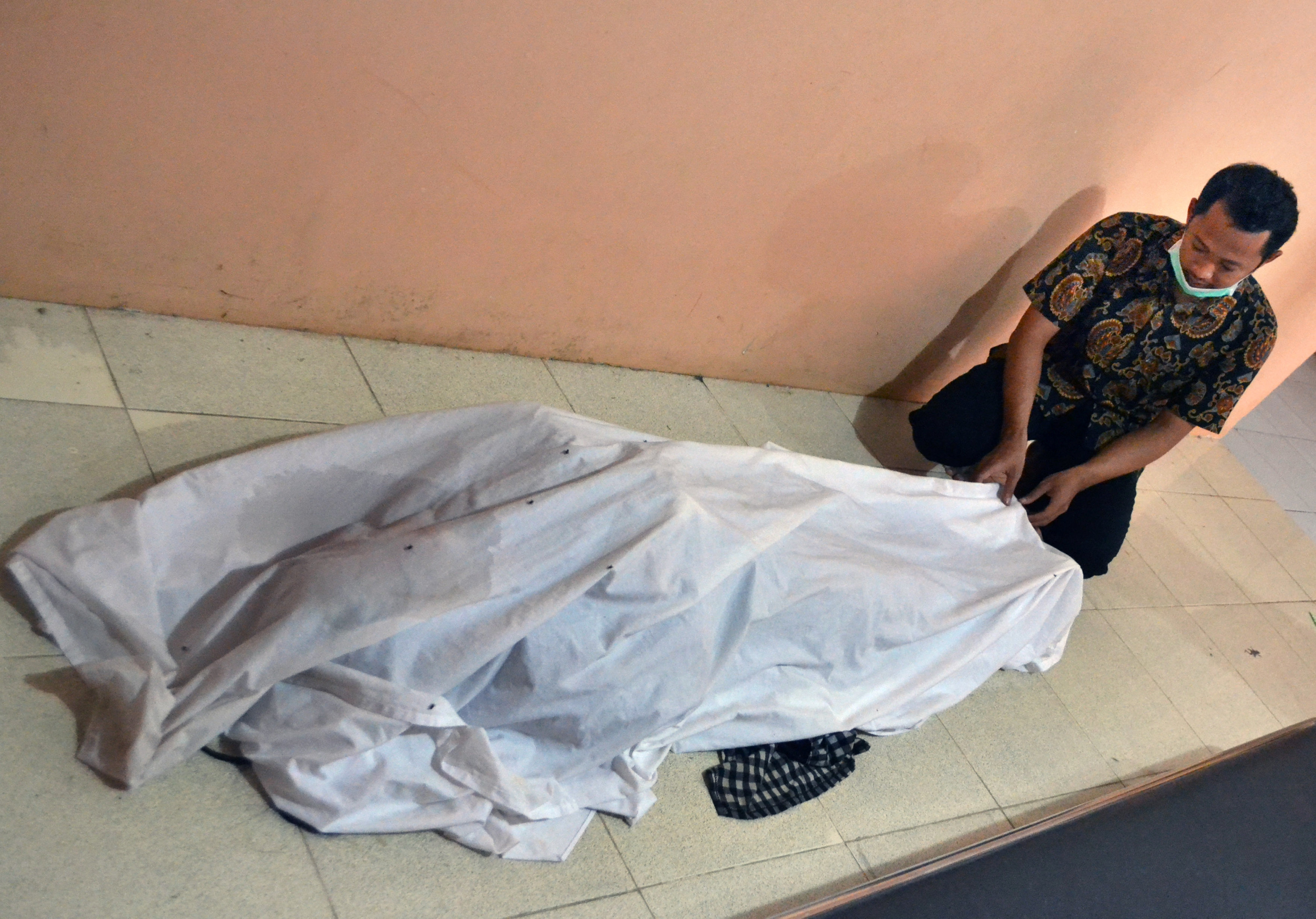 Un hombre cubre el cuerpo de una víctima. (Antara Foto/Muhammad Bagus Khoirunas/ via REUTERs)