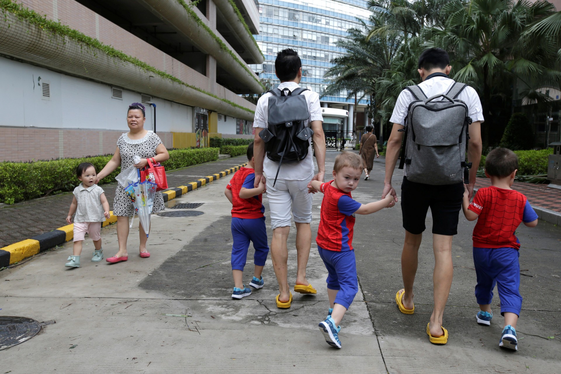 Una niña mira a An Hui y su compañero Ye Jianbin caminando con sus hijos, An Zhizhong, An Zhiya y An Zhifei en una comunidad residencial en Shenzhen, provincia de Guangdong, China, 17 de septiembre de 2018.