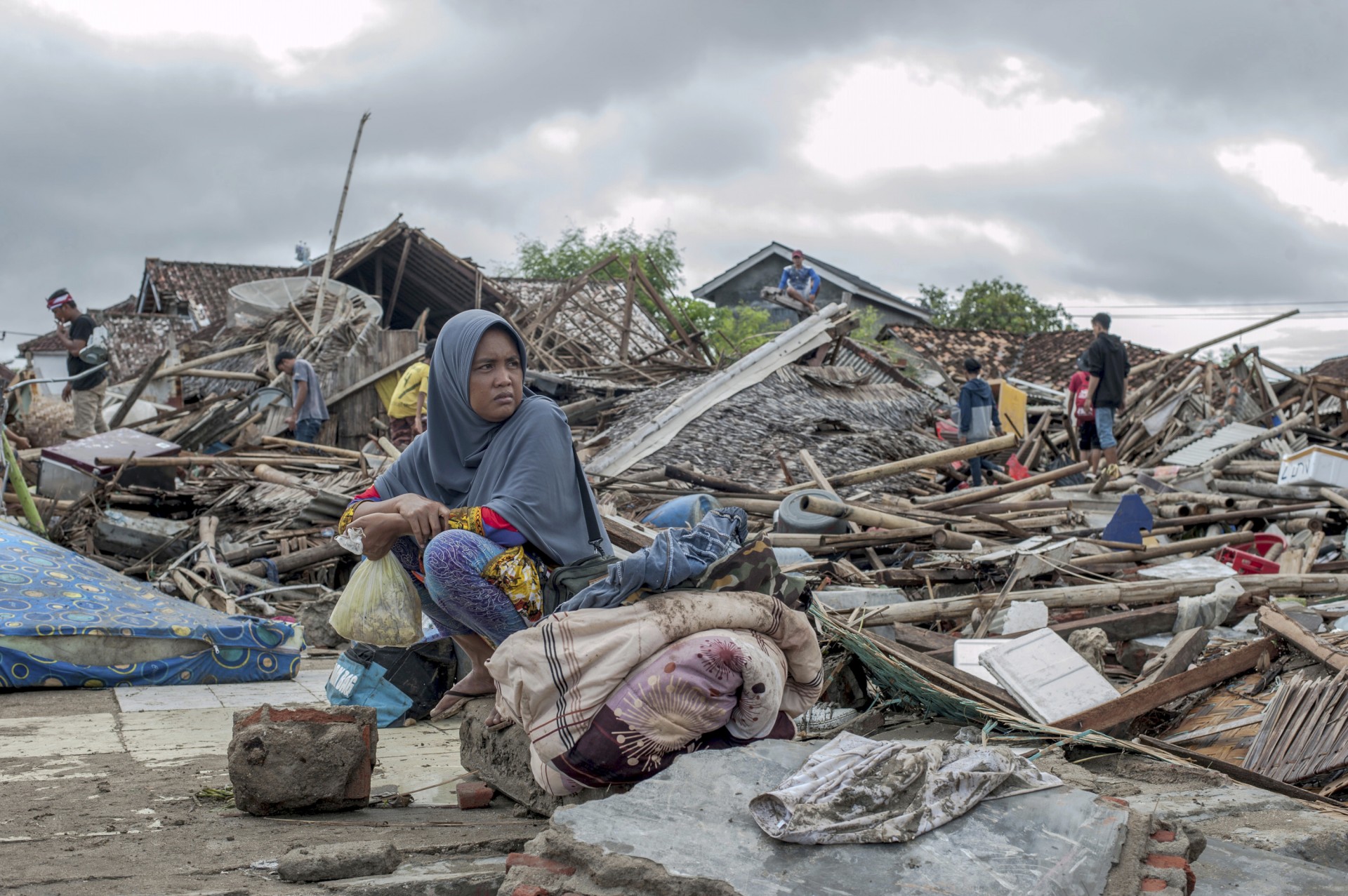 Una sobreviviente del tsunami se sienta en un pedazo de escombros mientras rescata artículos de la ubicación de su casa en Sumur, Indonesia, el lunes 24 de diciembre de 2018.