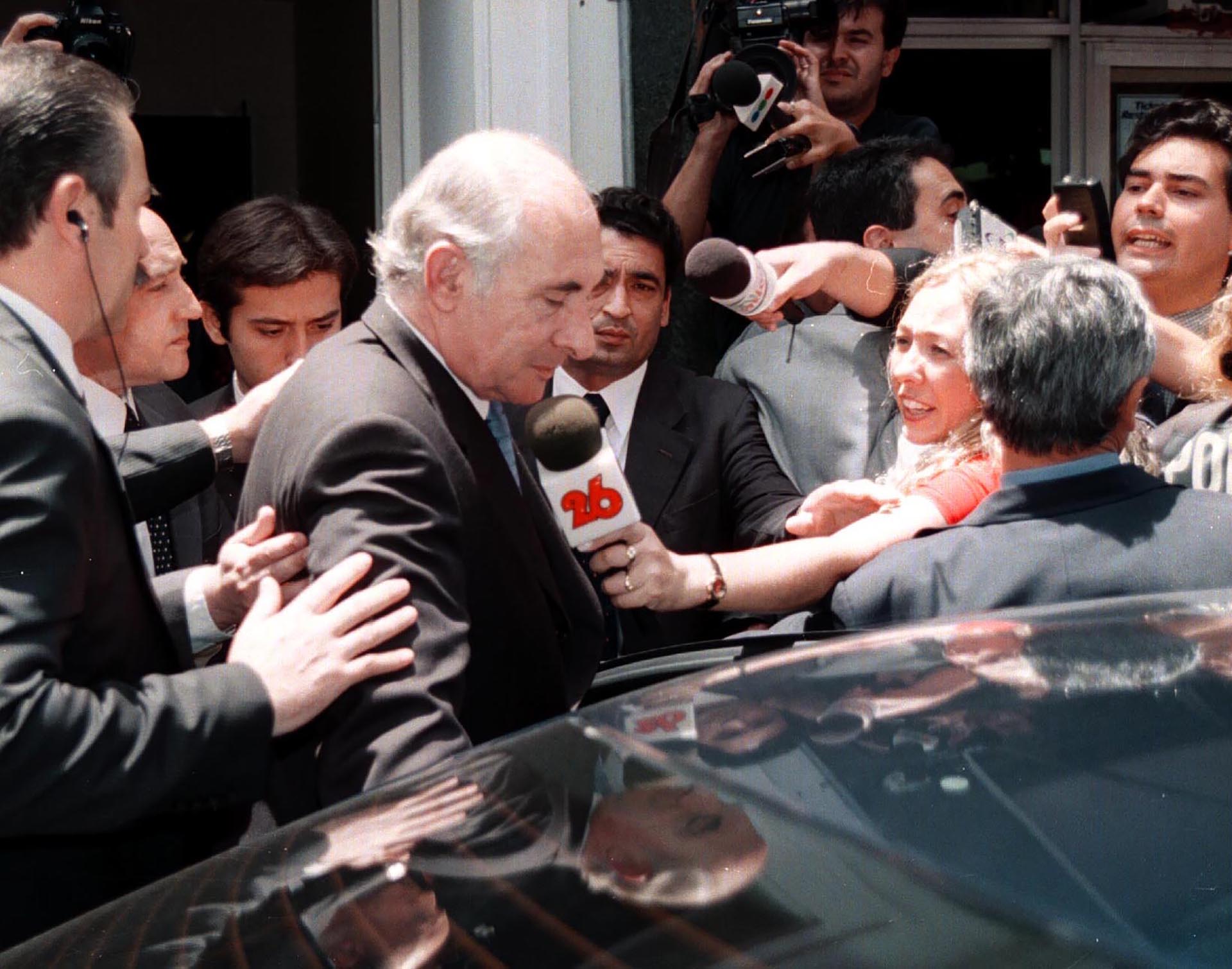 El ex mandatario al salir de la sede de Cáritas, asediado por la prensa. Previa a las jornadas que marcaron el fin de su presidencia, se reunió con representantes de la Iglesia, organizaciones sociales y políticas
